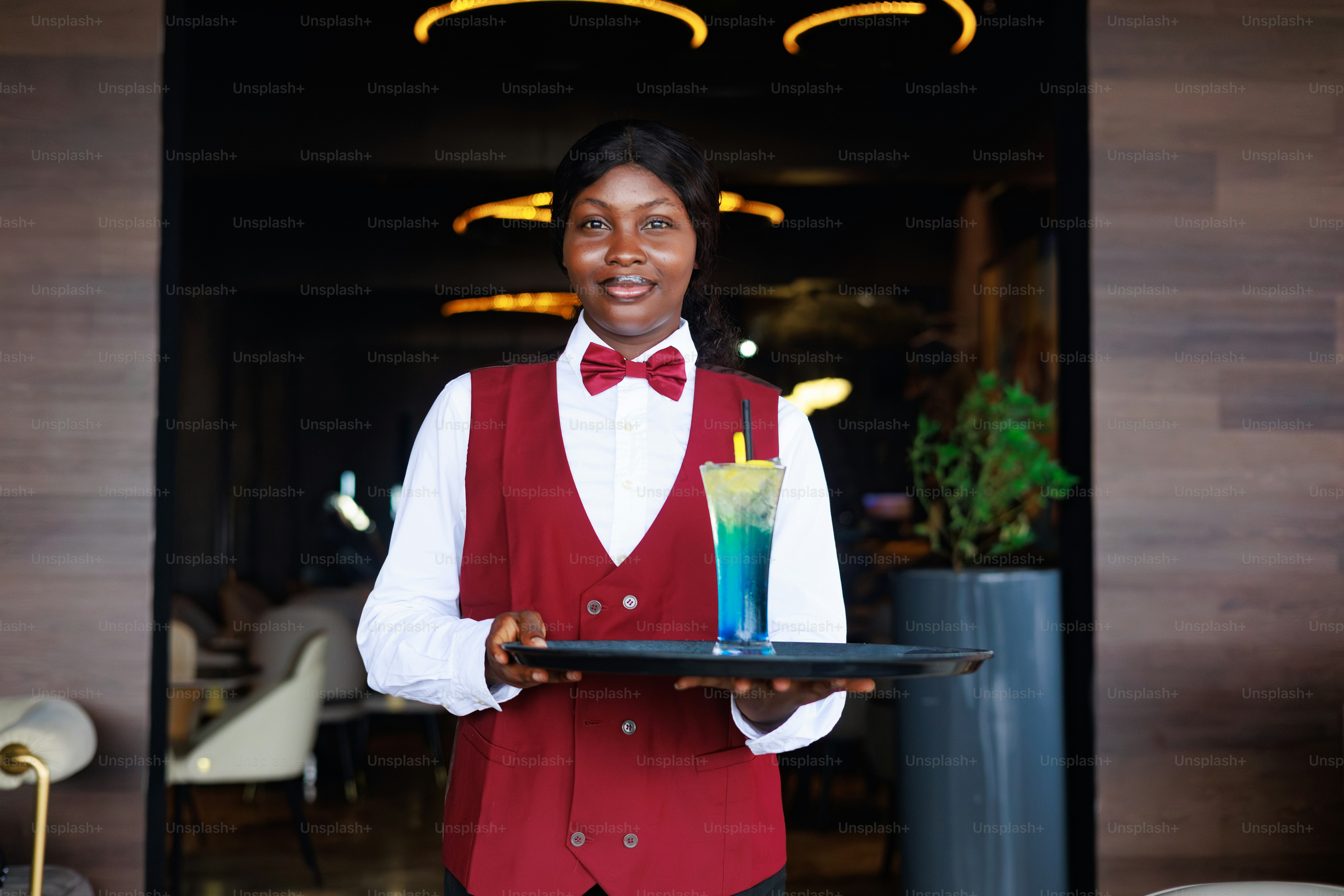 A waitress presents a cocktail on a tray.
