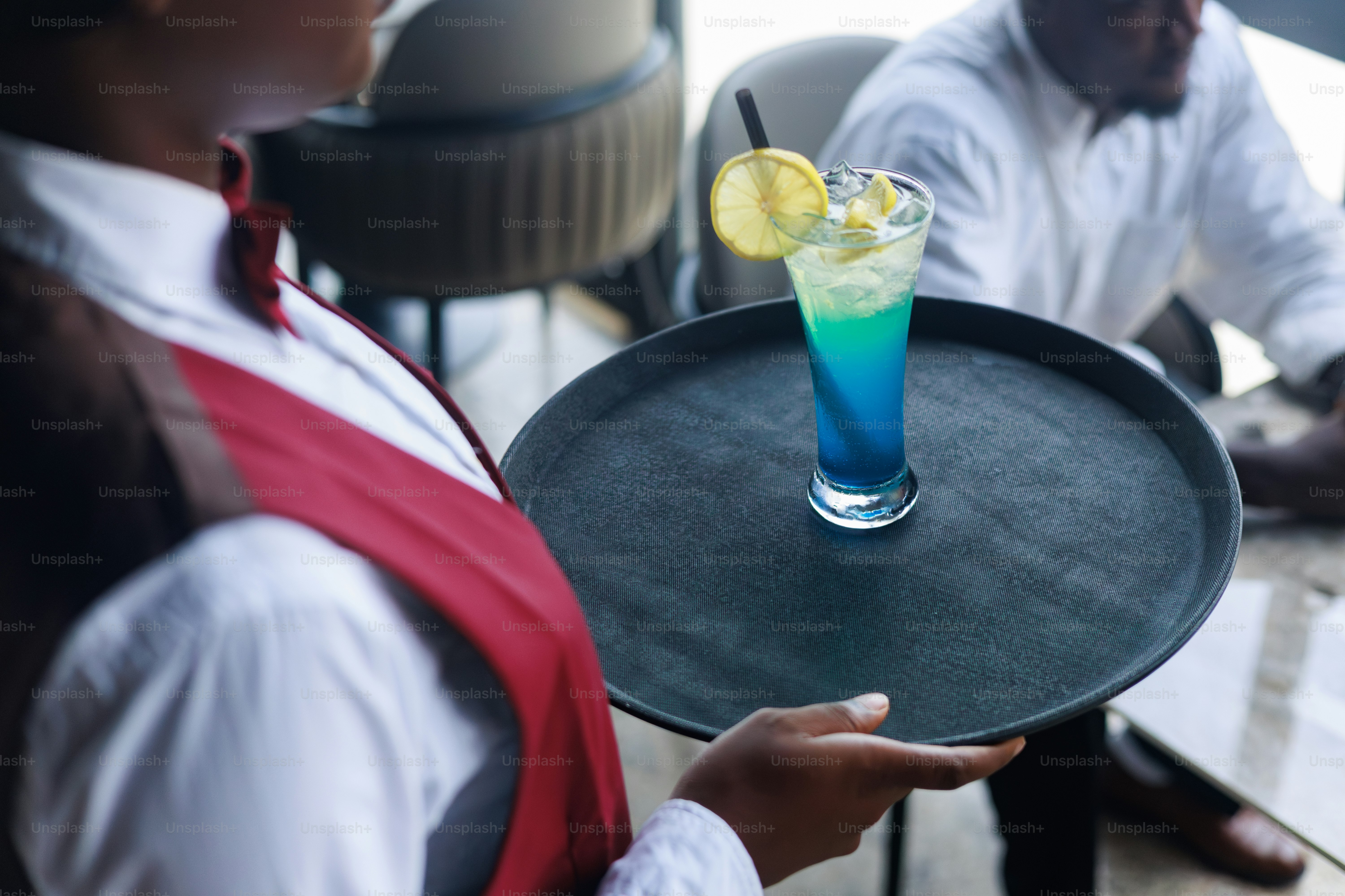 A waiter carries a cocktail on a tray.