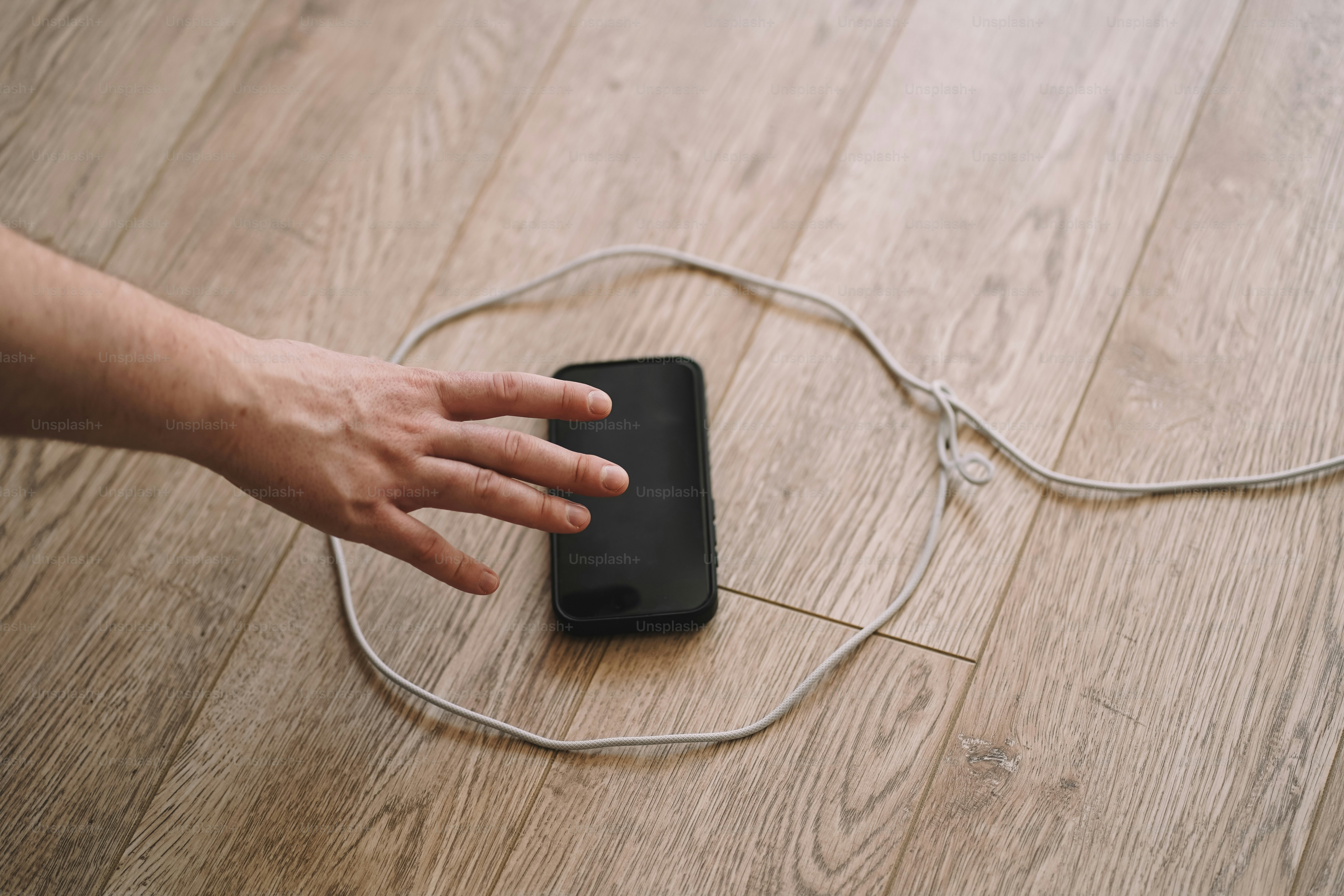 A hand reaches for a cell phone.