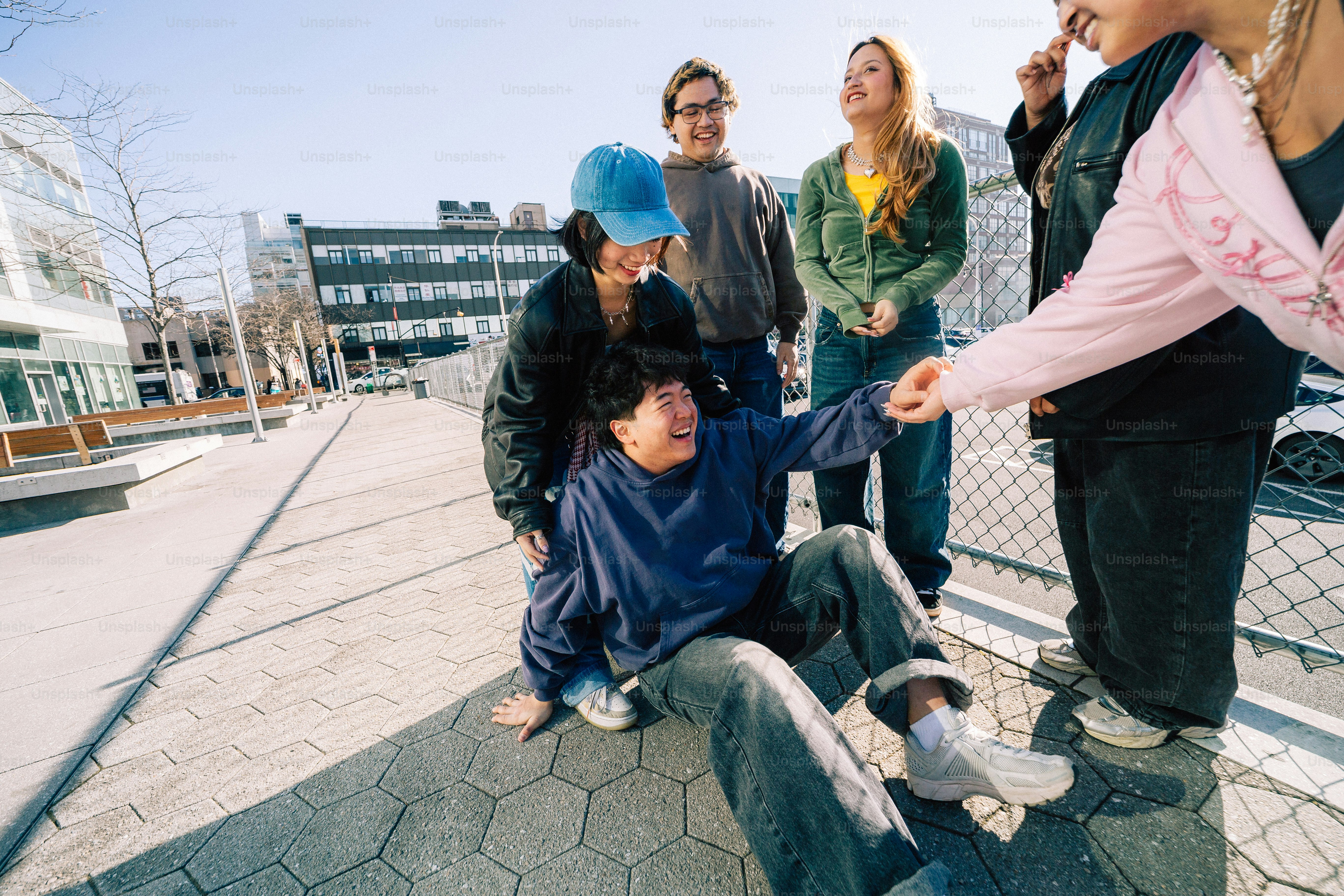 Friends laugh and help a person sitting on the ground.