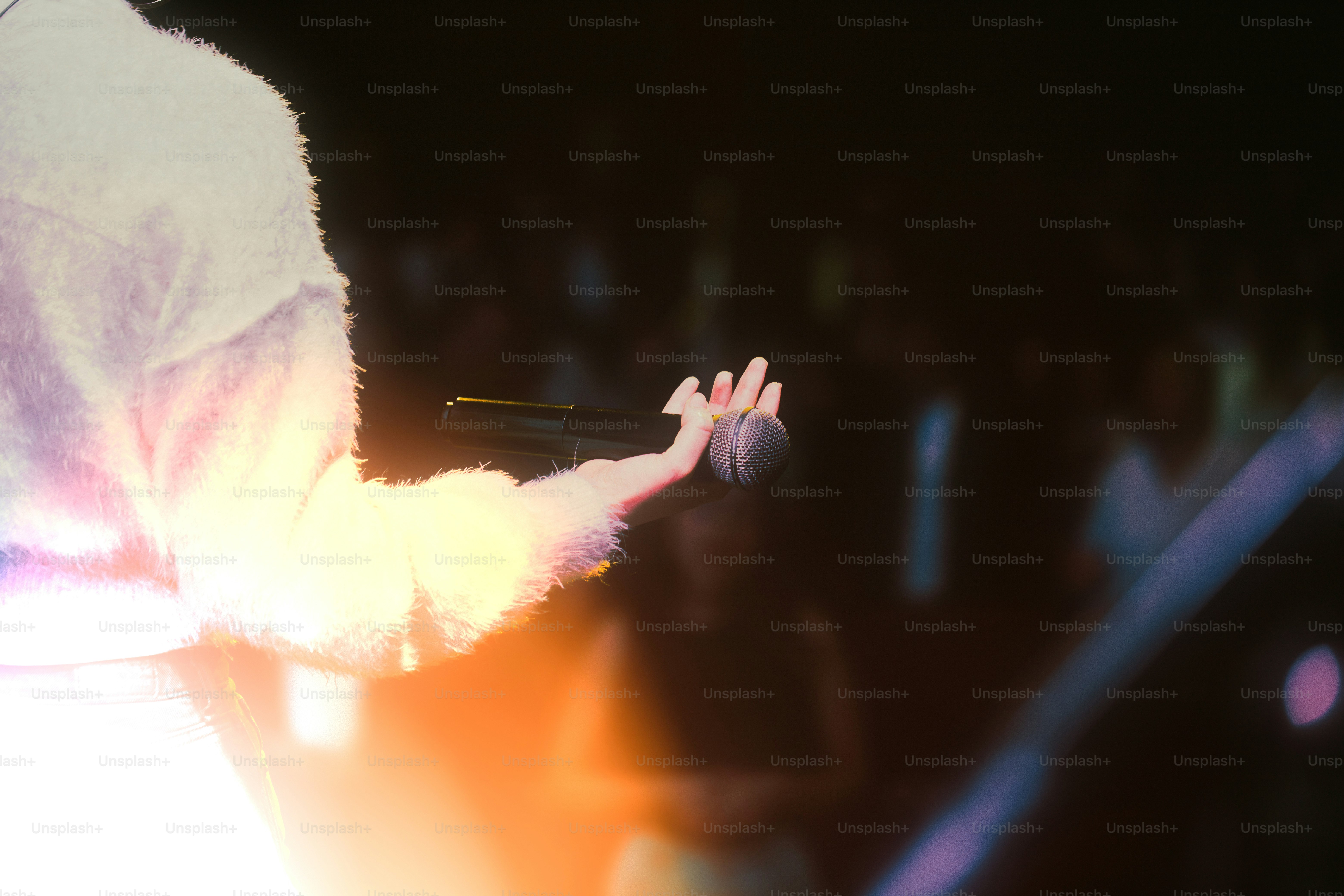 Singer holding microphone on a dimly lit stage. photo – Music Image on ...