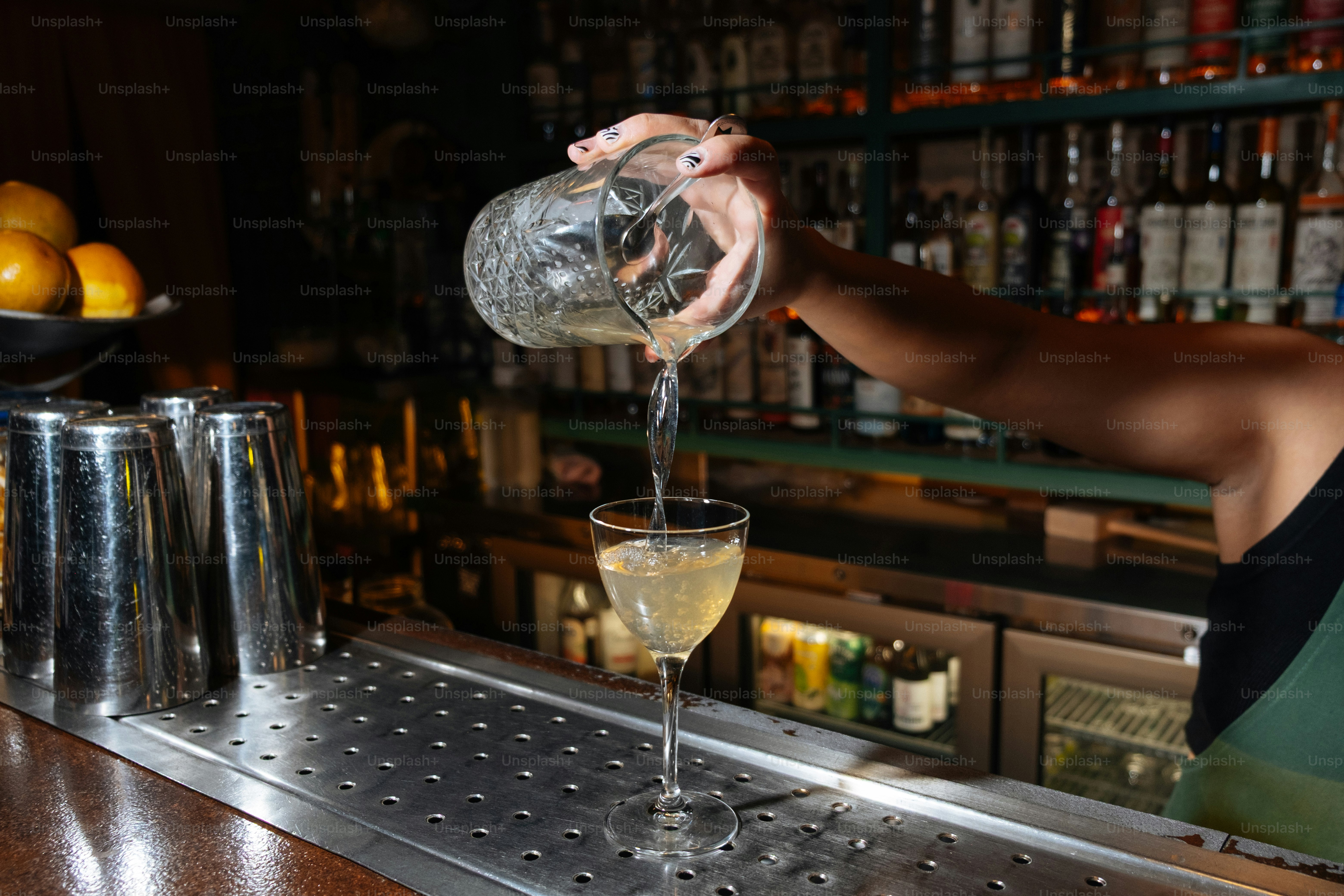 A bartender is pouring a cocktail.
