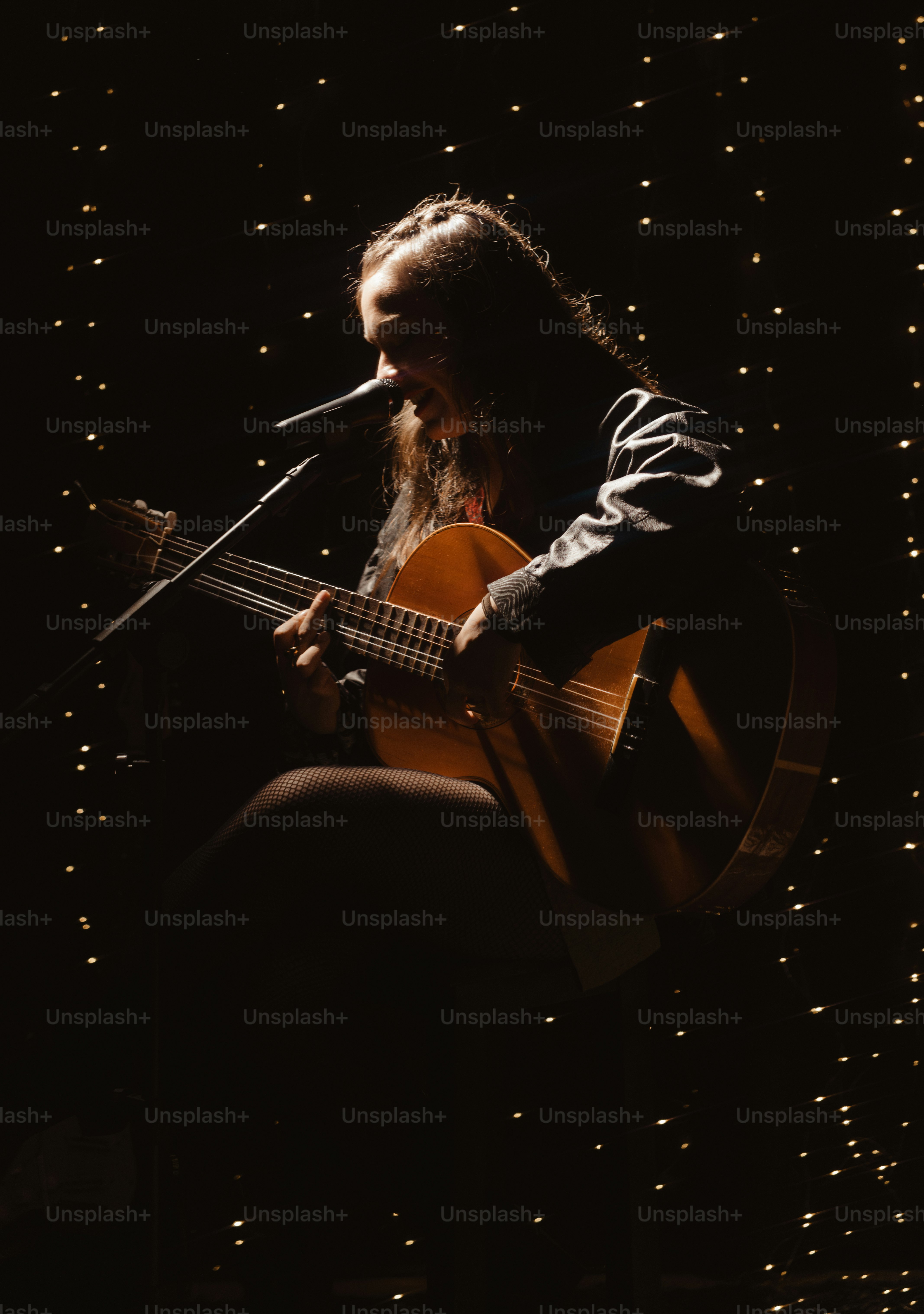 Ein Musiker spielt Gitarre auf einer dunklen Bühne.