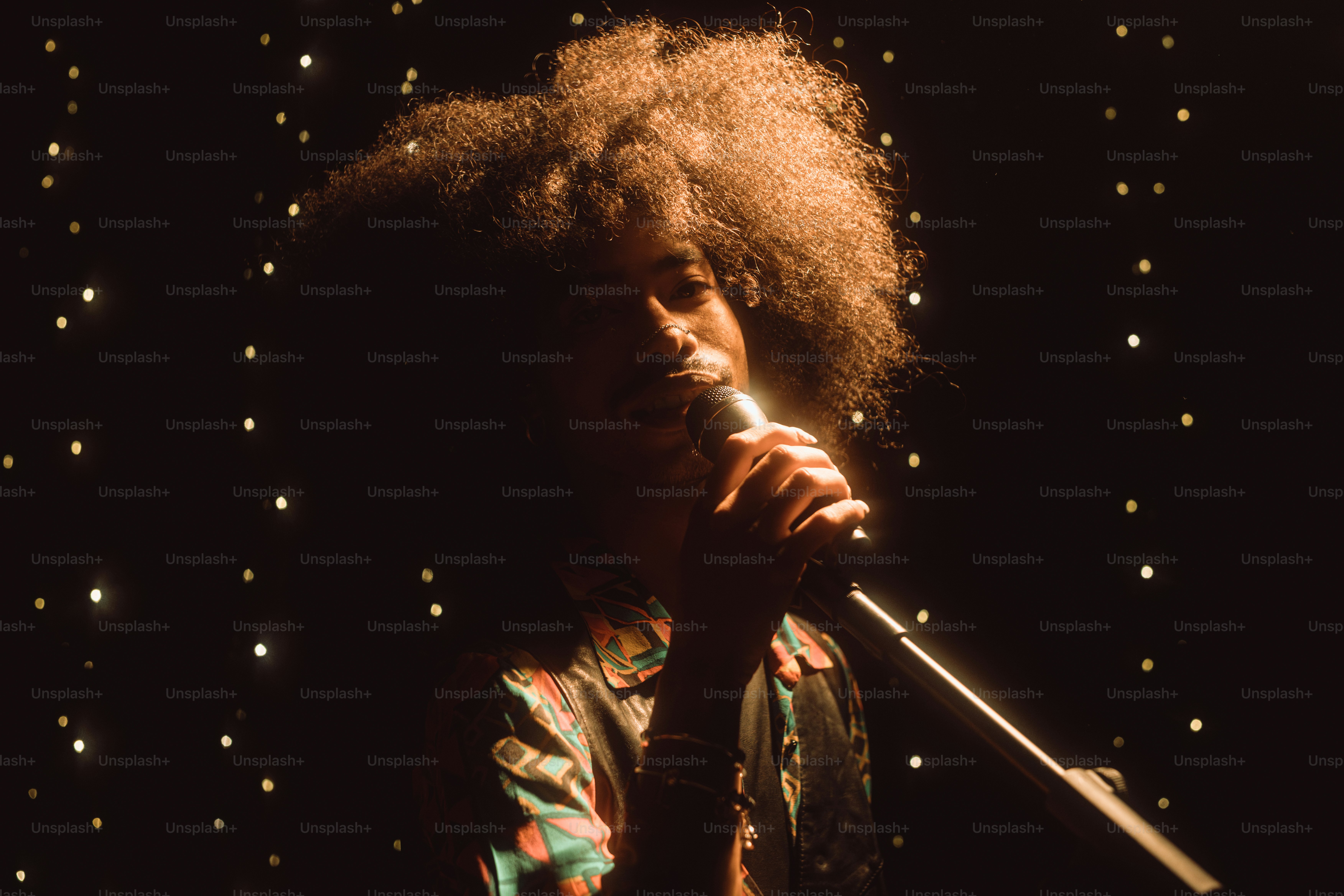 A singer performs into a microphone under stage lights. photo – Music ...