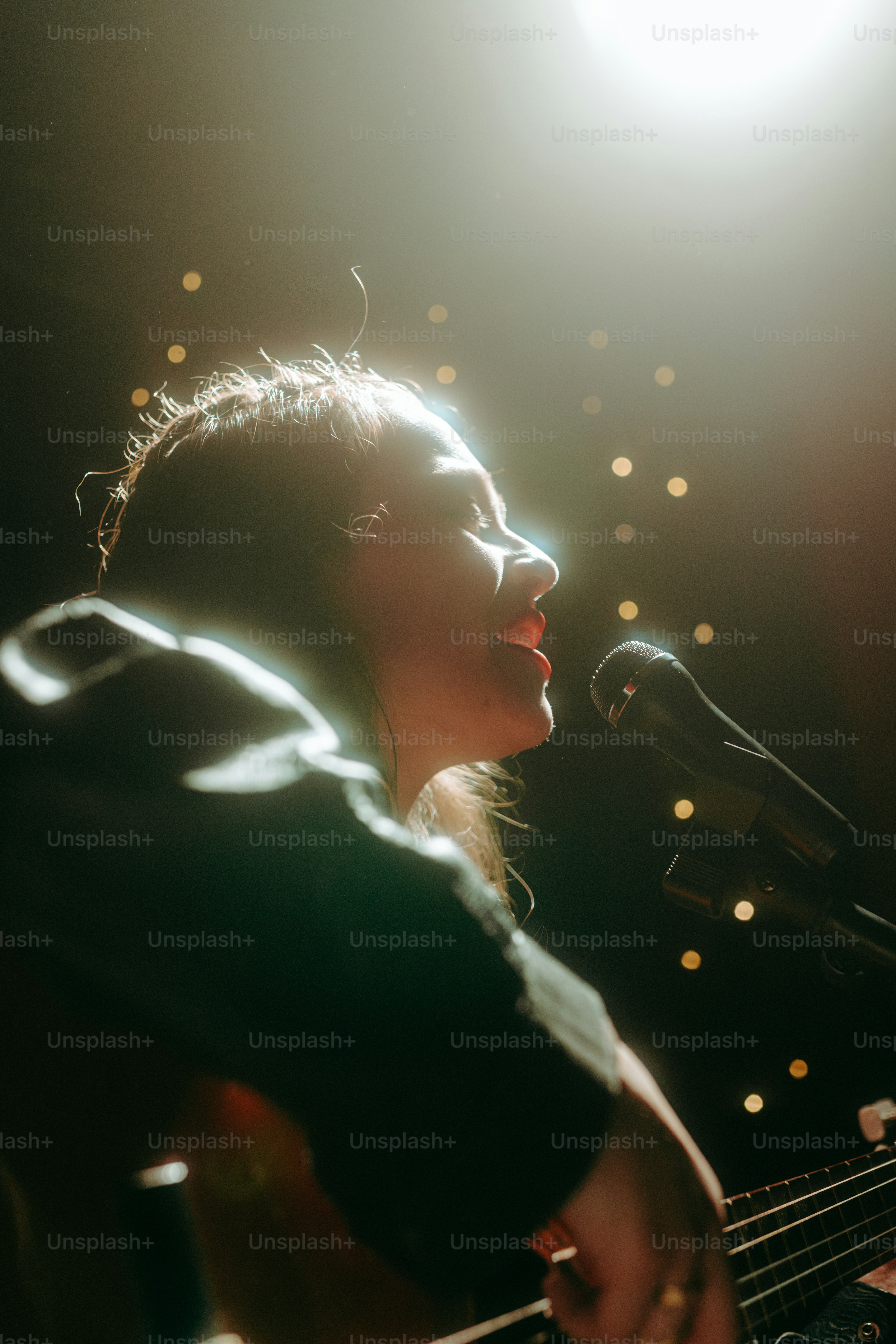 A singer performs into a microphone under stage lights.