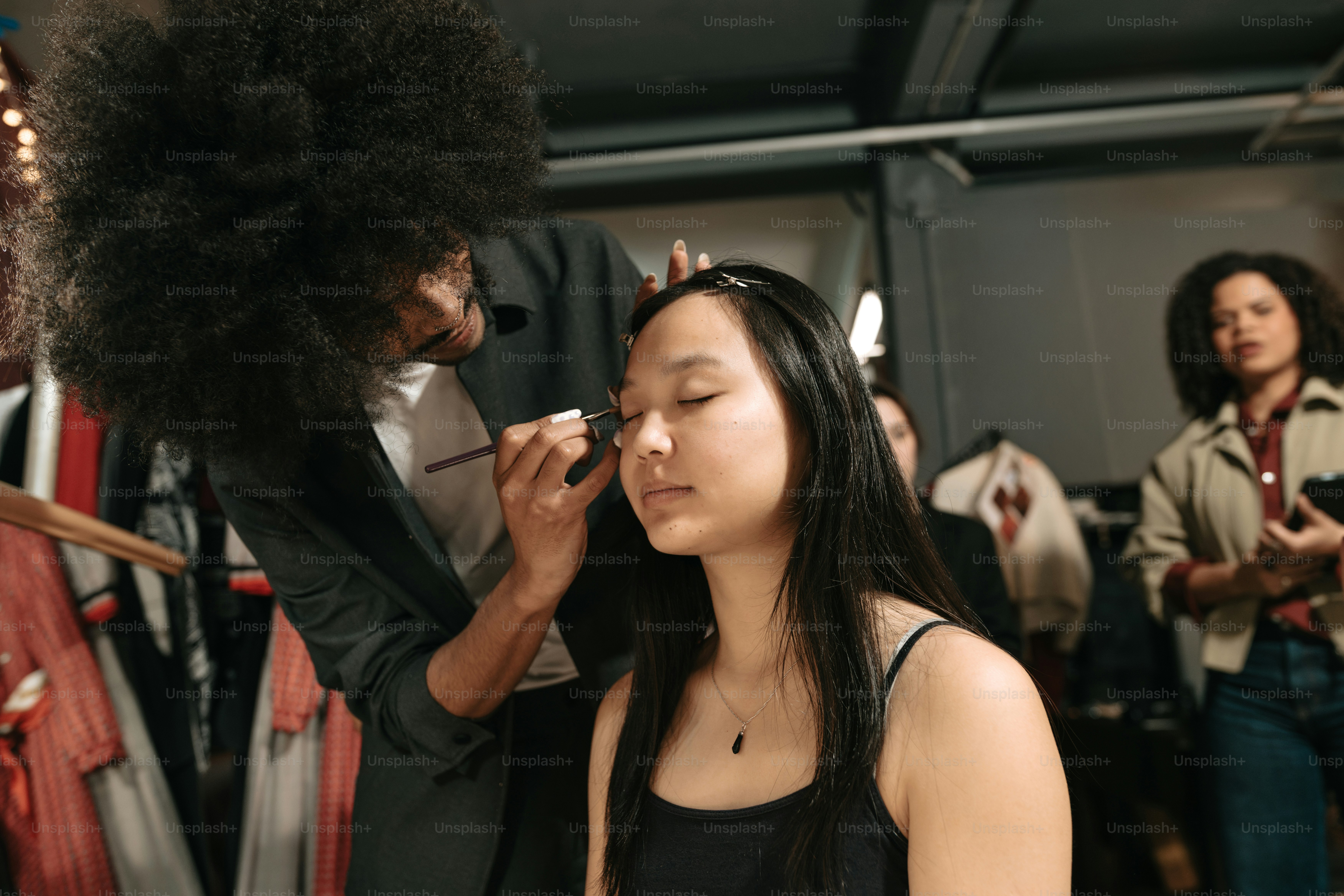 Makeup artist working on a model's eyes backstage. photo – Fashion ...