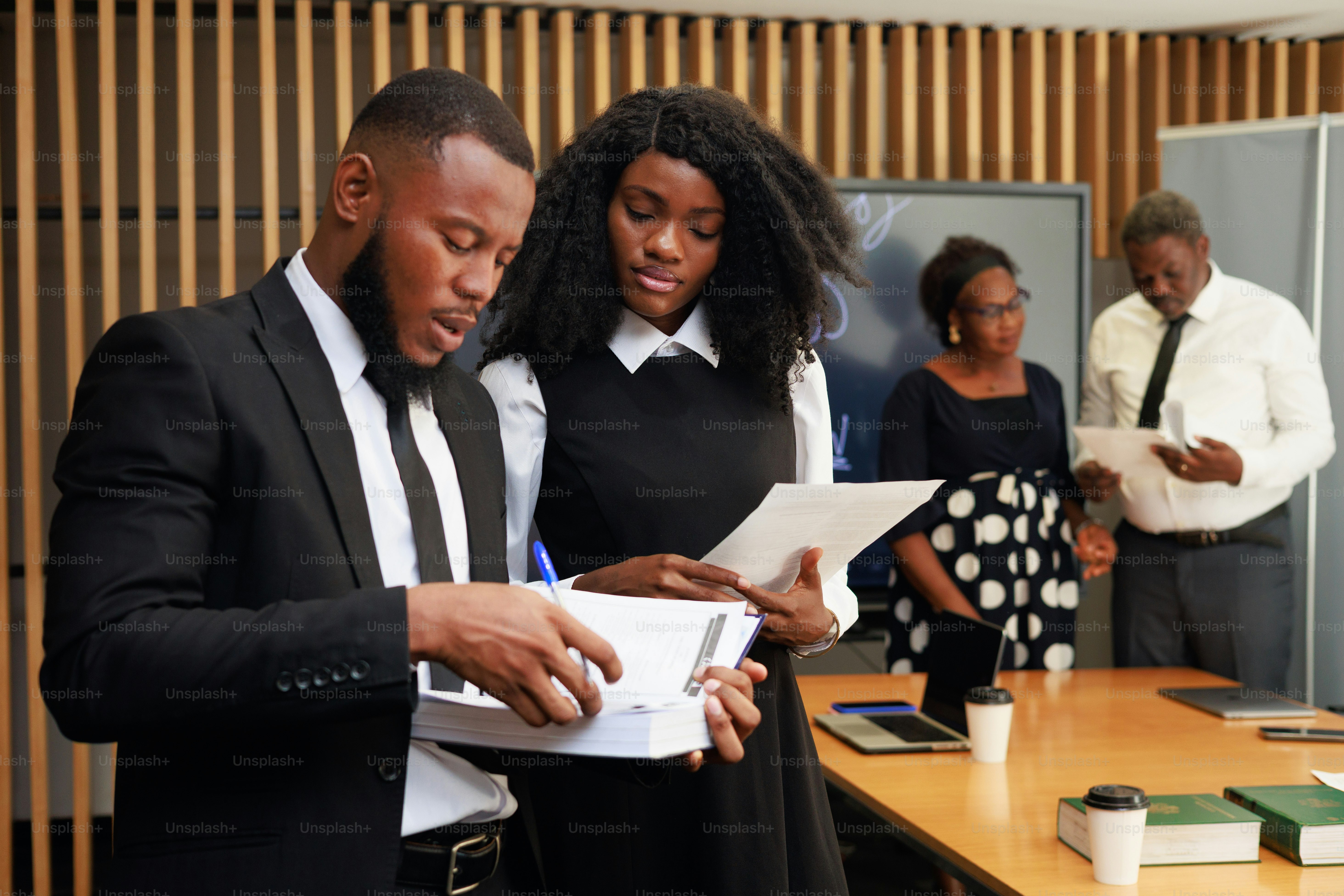 Two people carefully reviewing printed paperwork and documents at a desk