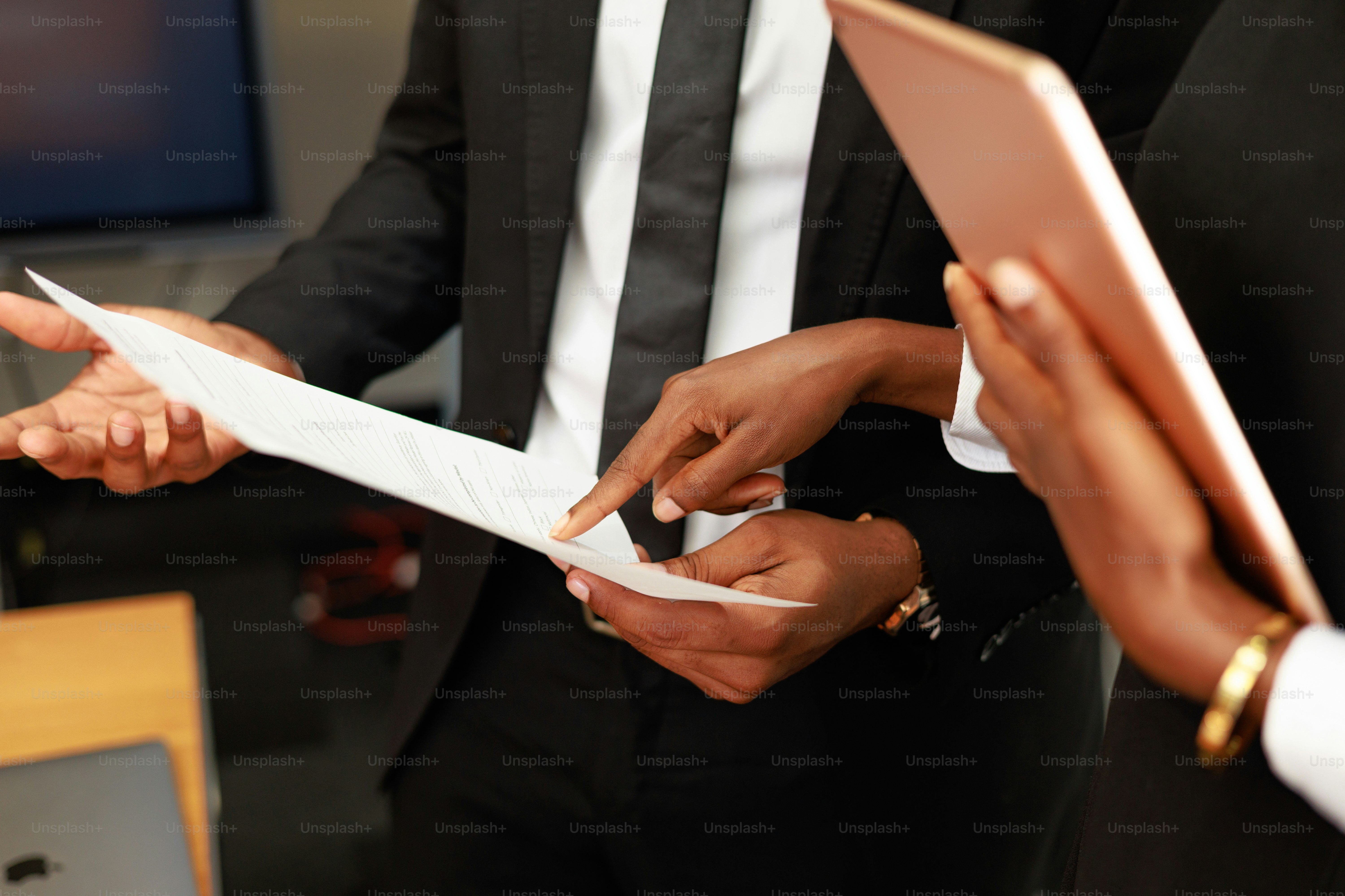 People in suits are discussing a document.