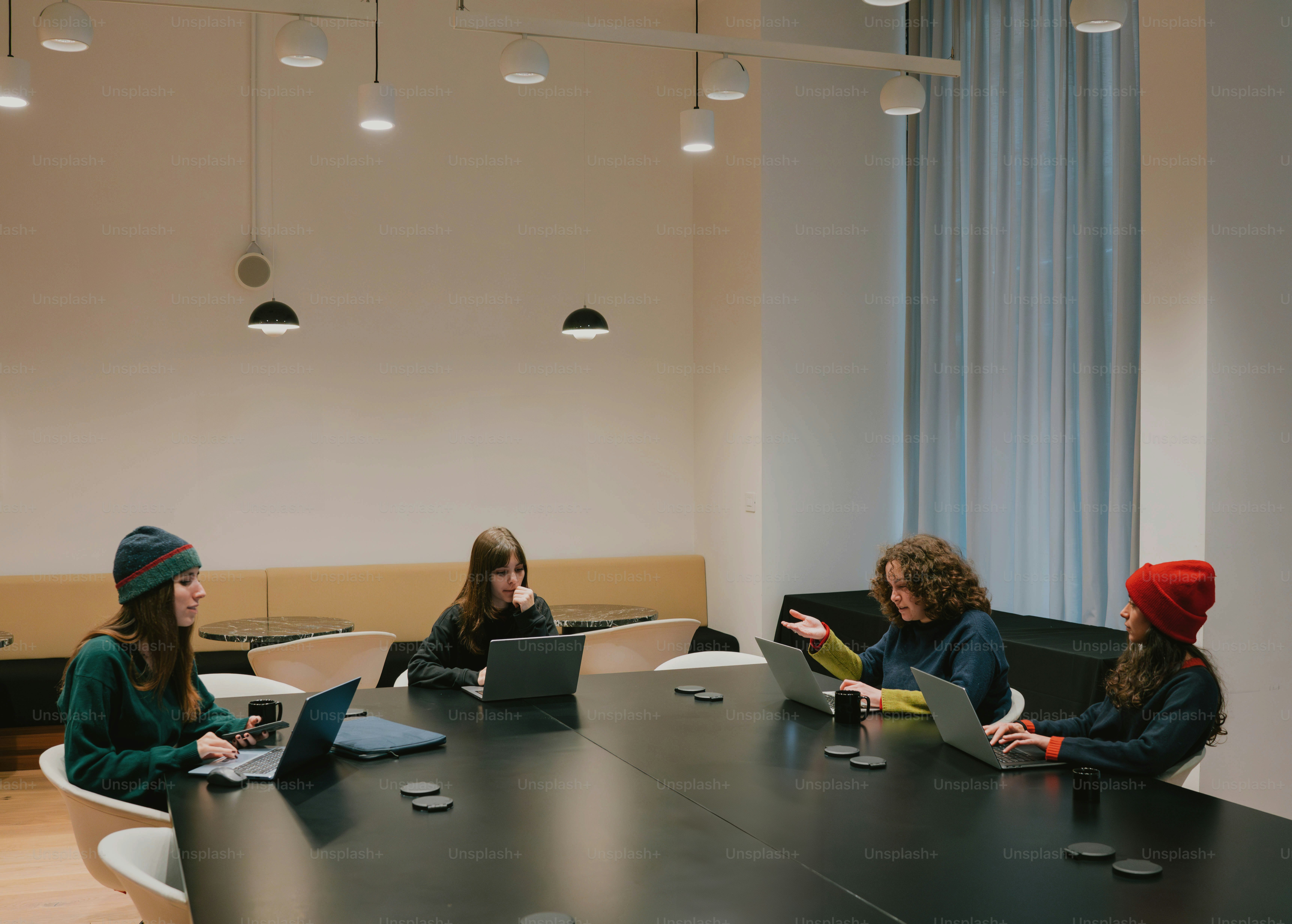 Quatro pessoas sentam-se ao redor de uma mesa usando laptops.