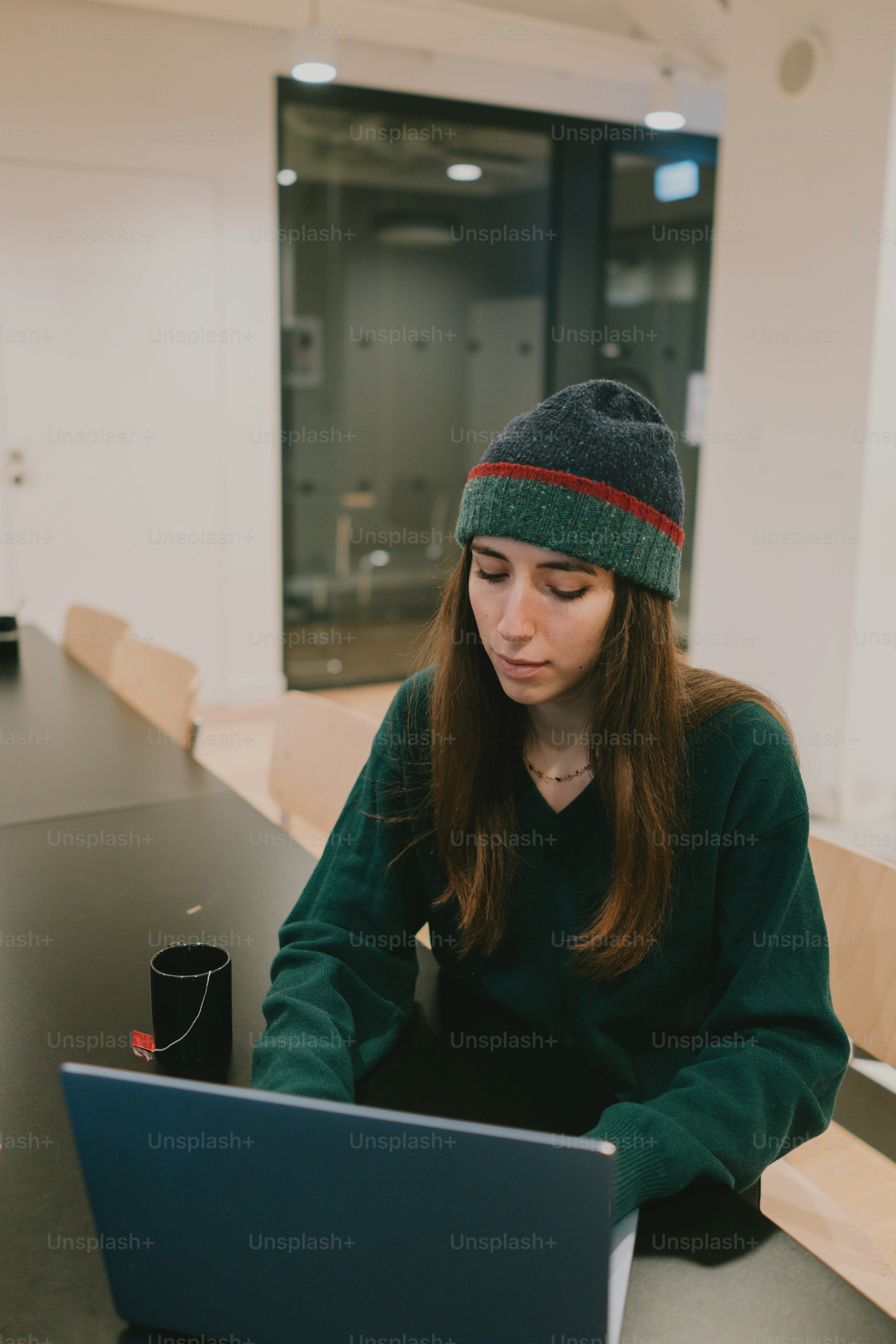 Woman wearing a beanie works on her laptop.