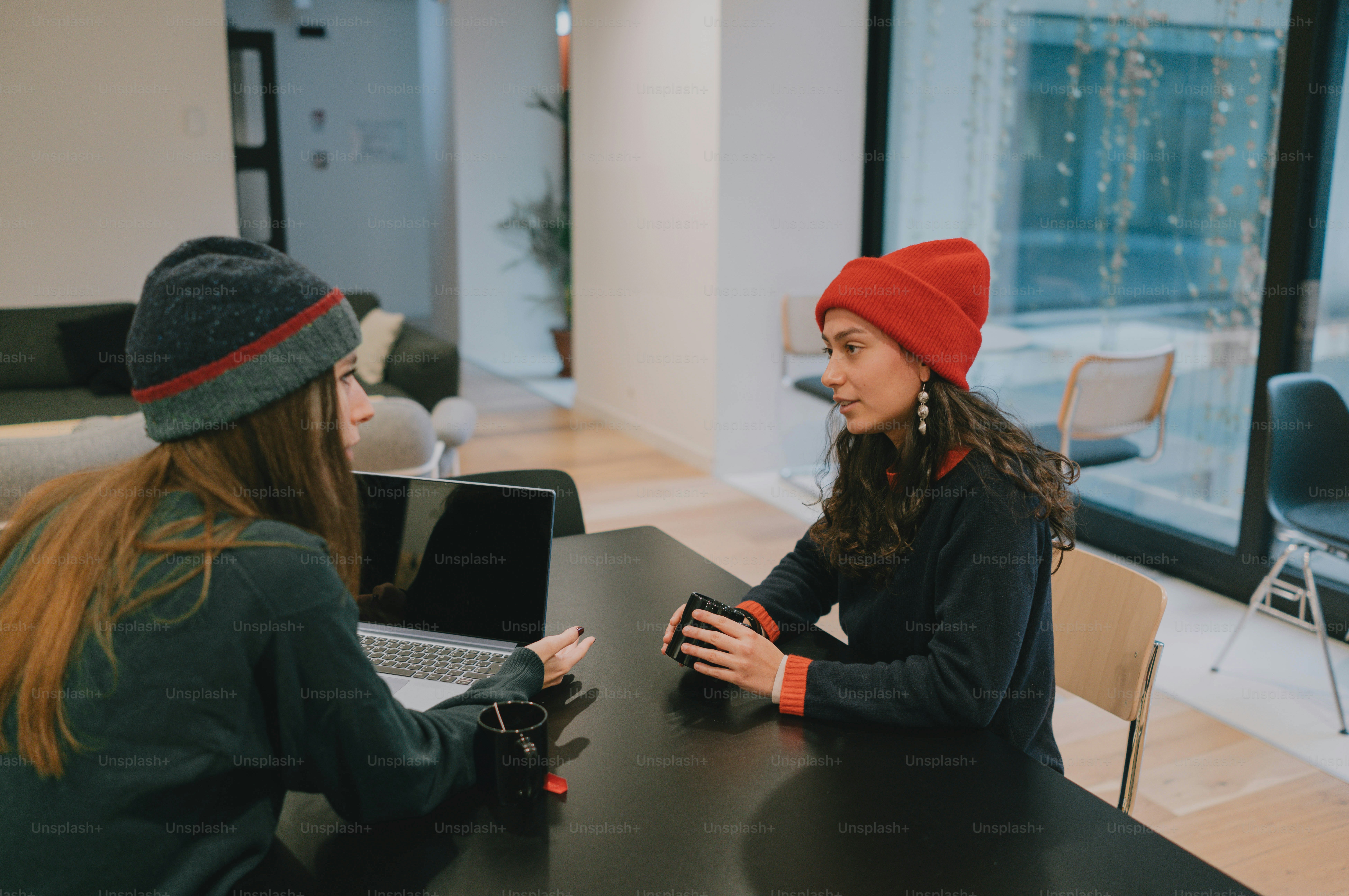 Two women are having a conversation at a table.