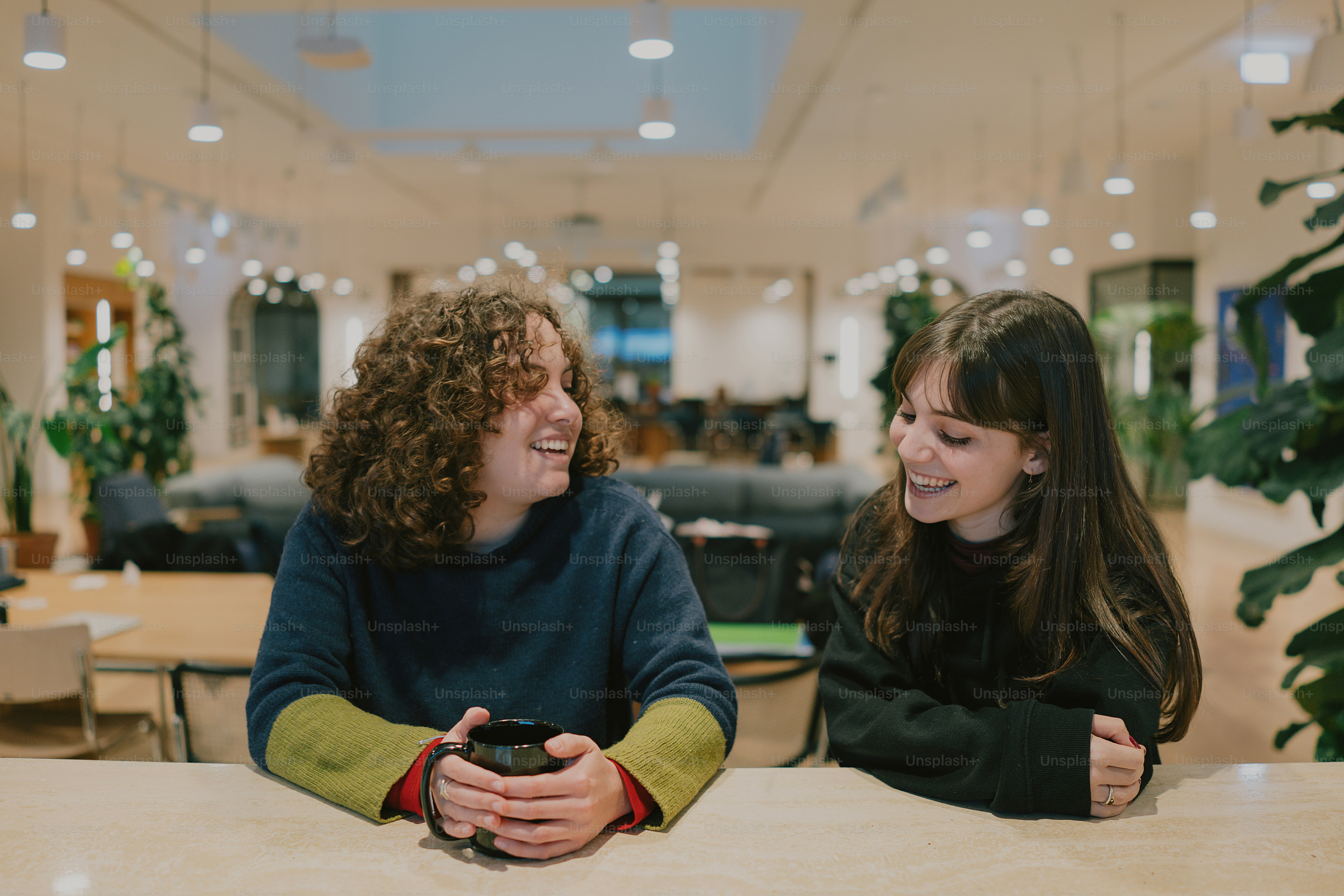 Two friends laughing in a bright workspace.