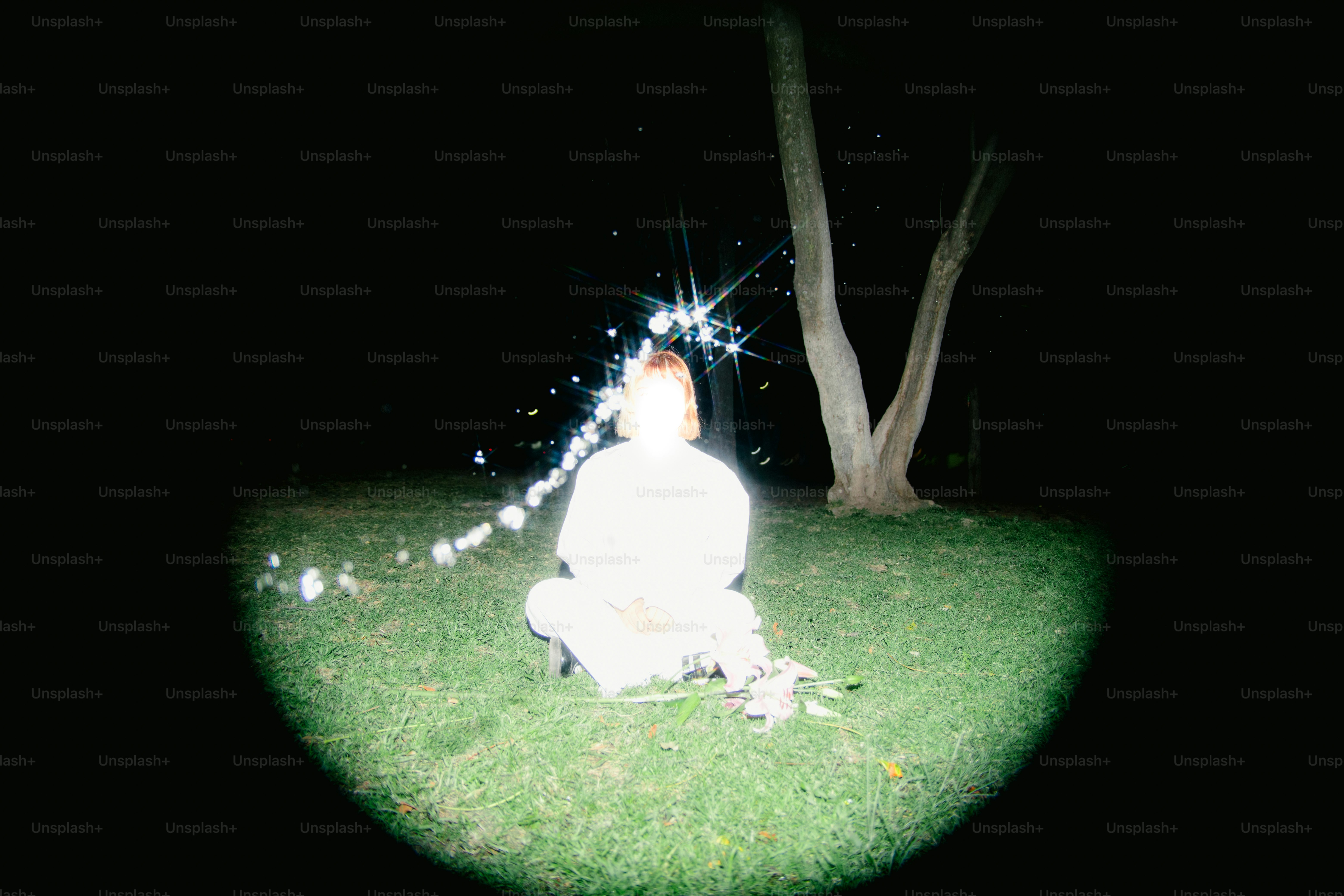 Eine Person sitzt umgeben von funkelnden Lichtern.