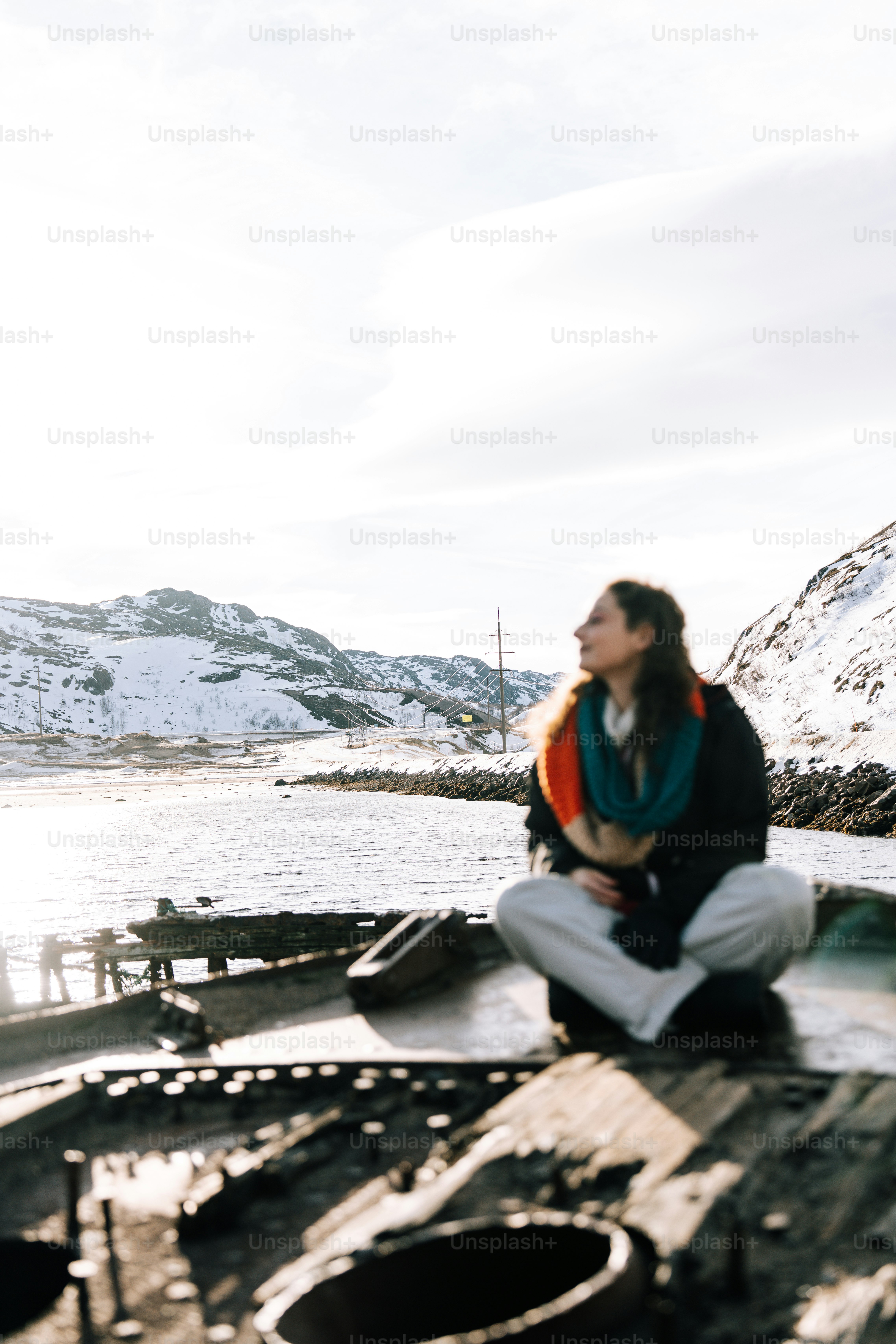 Woman sits peacefully, overlooking snowy mountains.