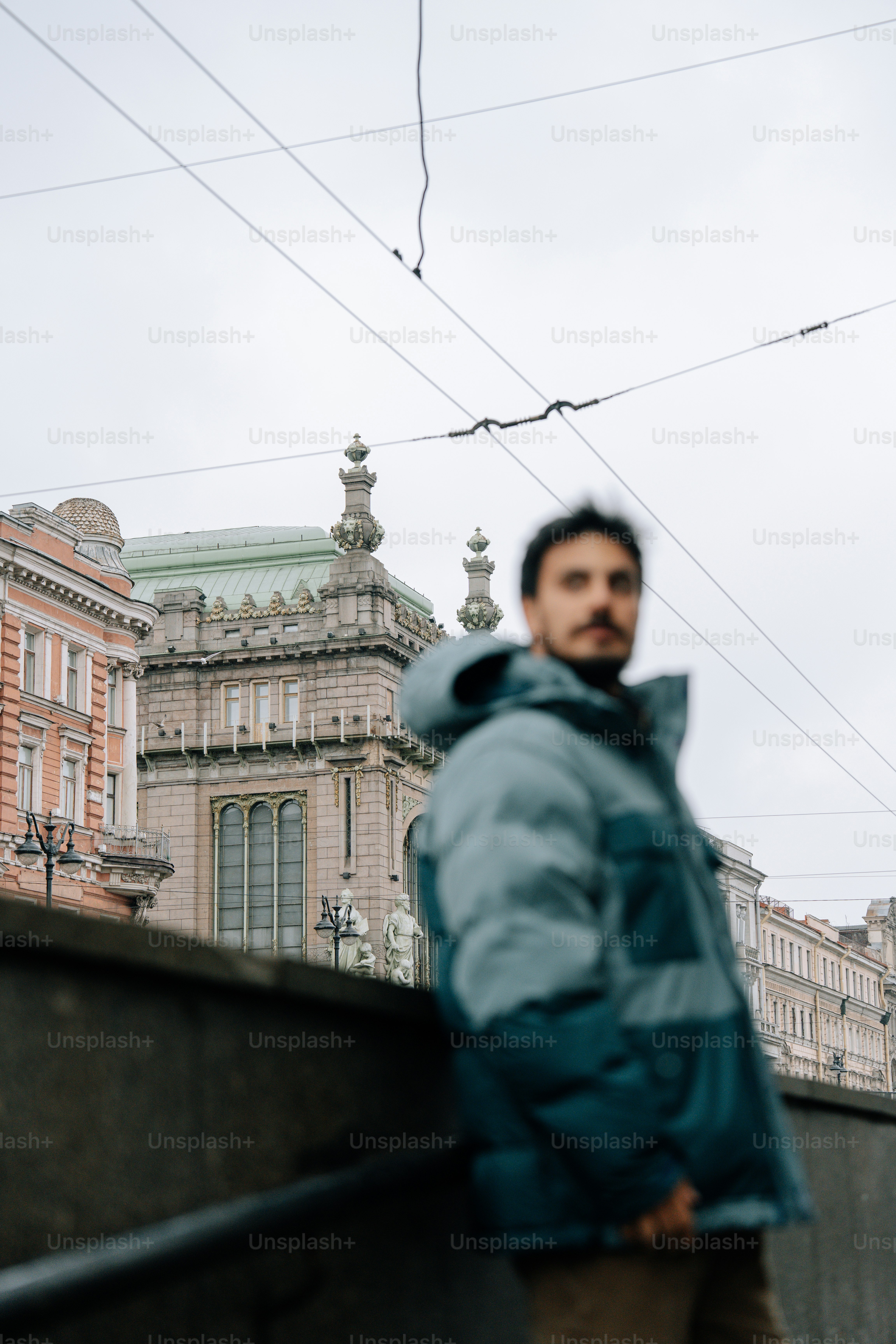 Man in jacket poses in front of a building.