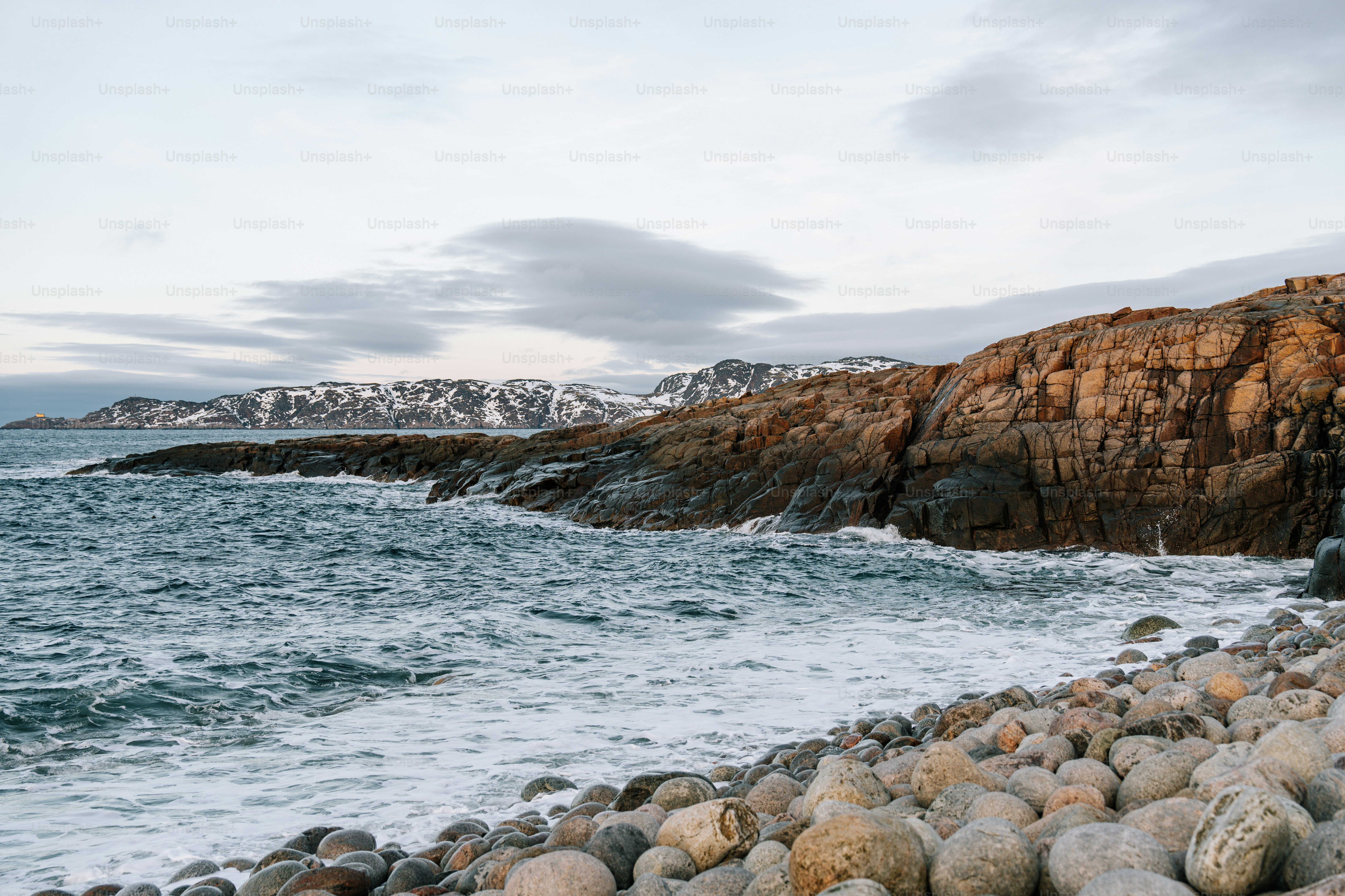 Rocky coastline with ocean waves and overcast sky.