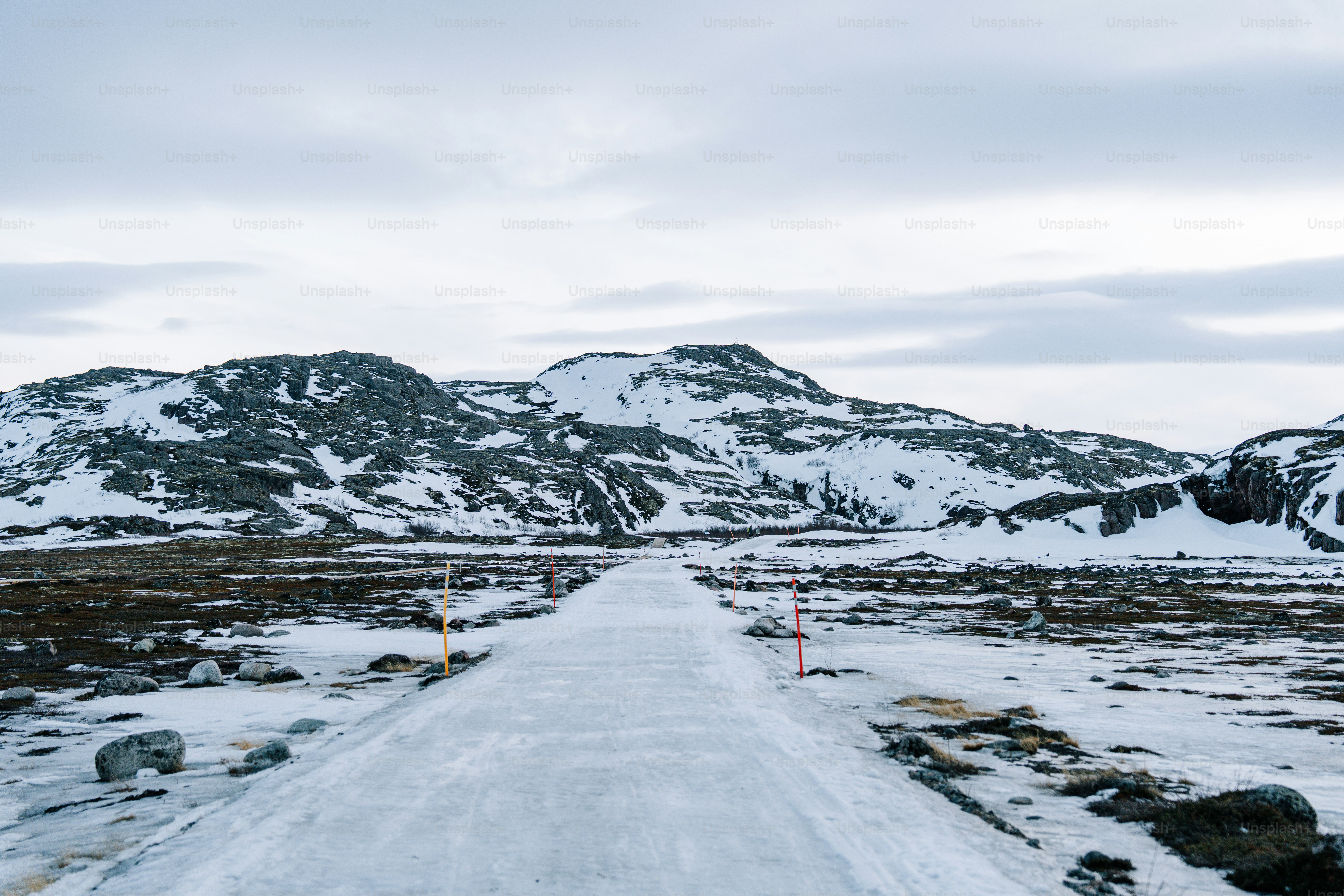 A snowy road leads to snow-covered mountains.