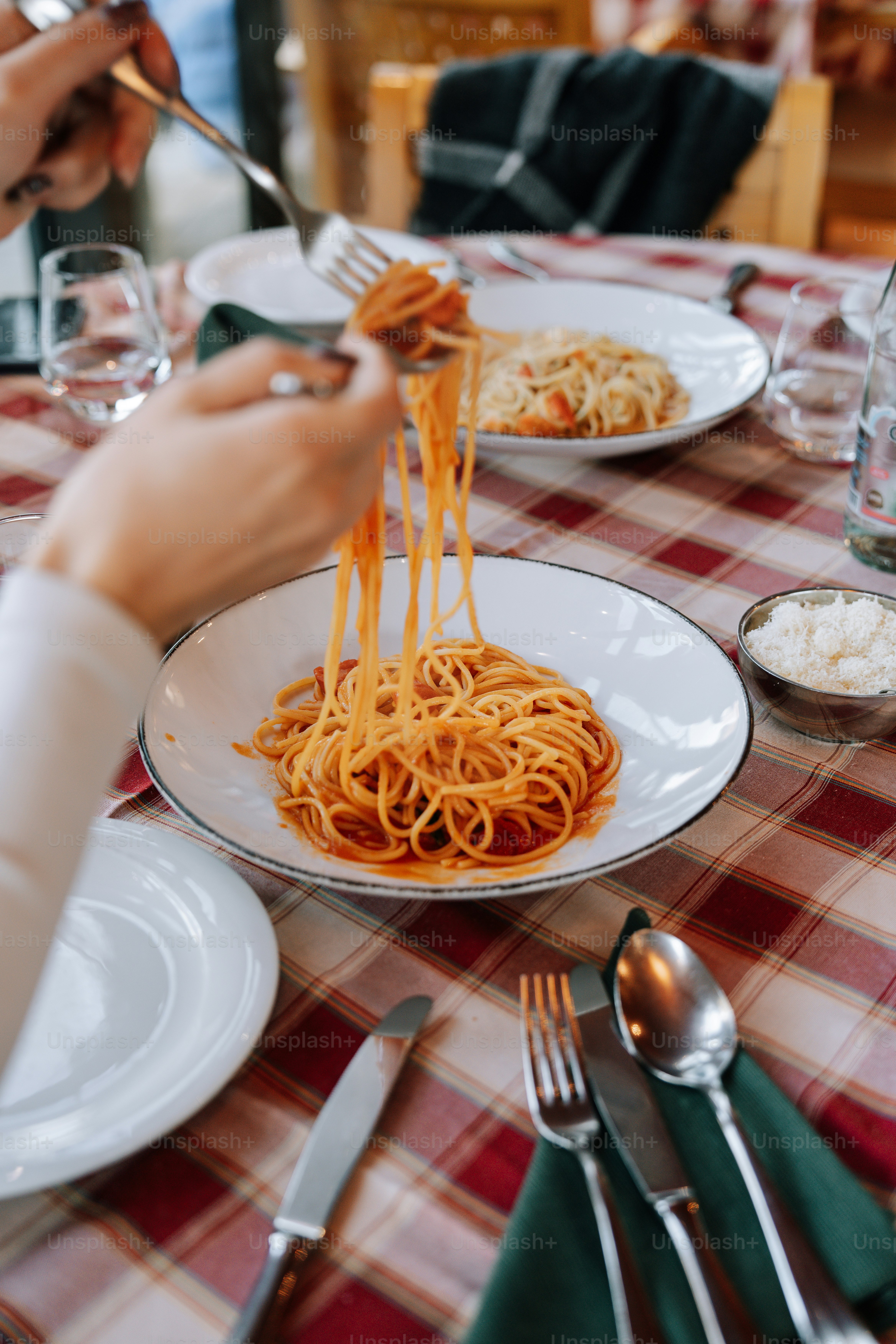 Eating spaghetti at a restaurant with red checkered tablecloth.