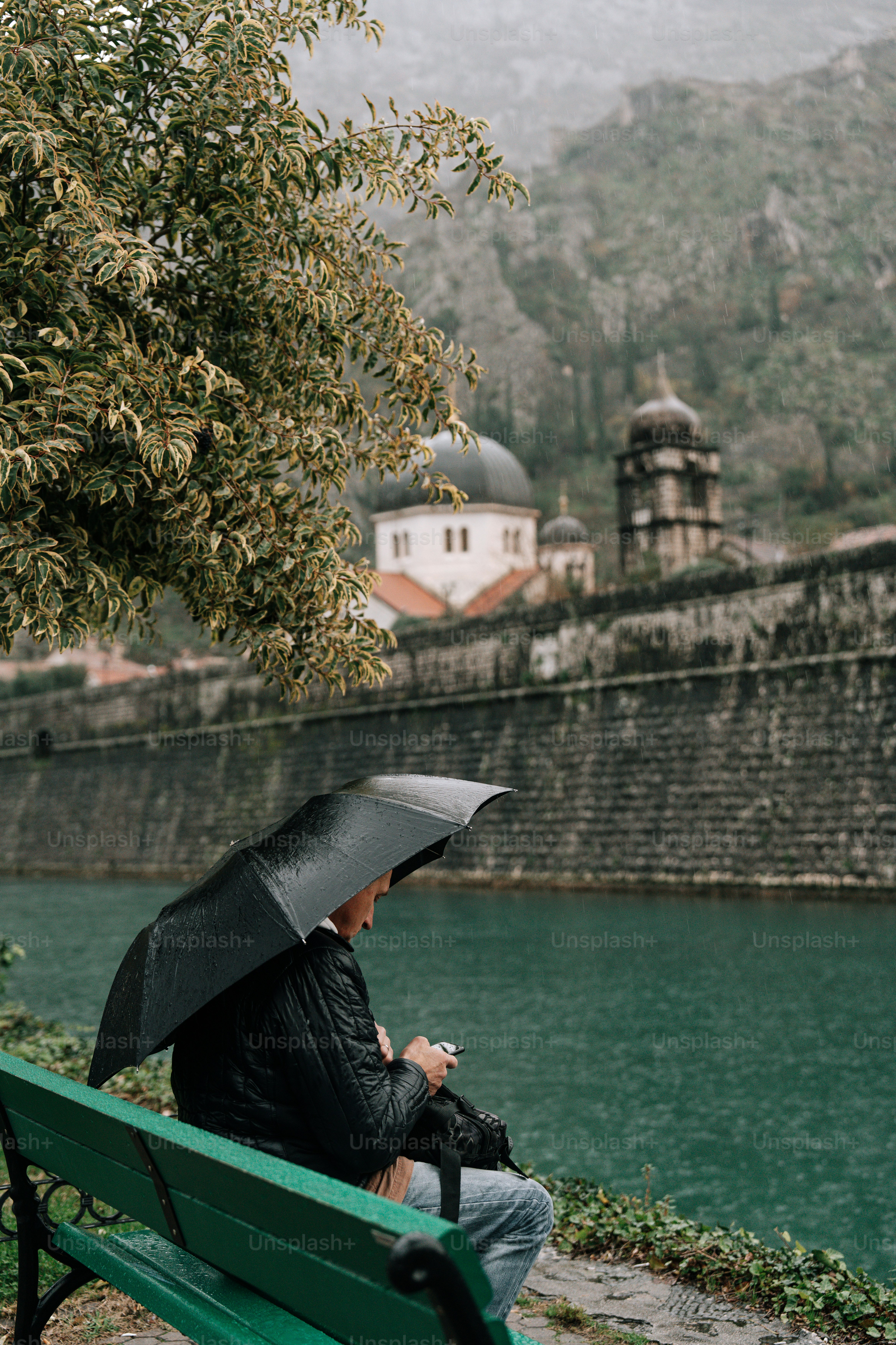 Person sits under umbrella near a body of water.