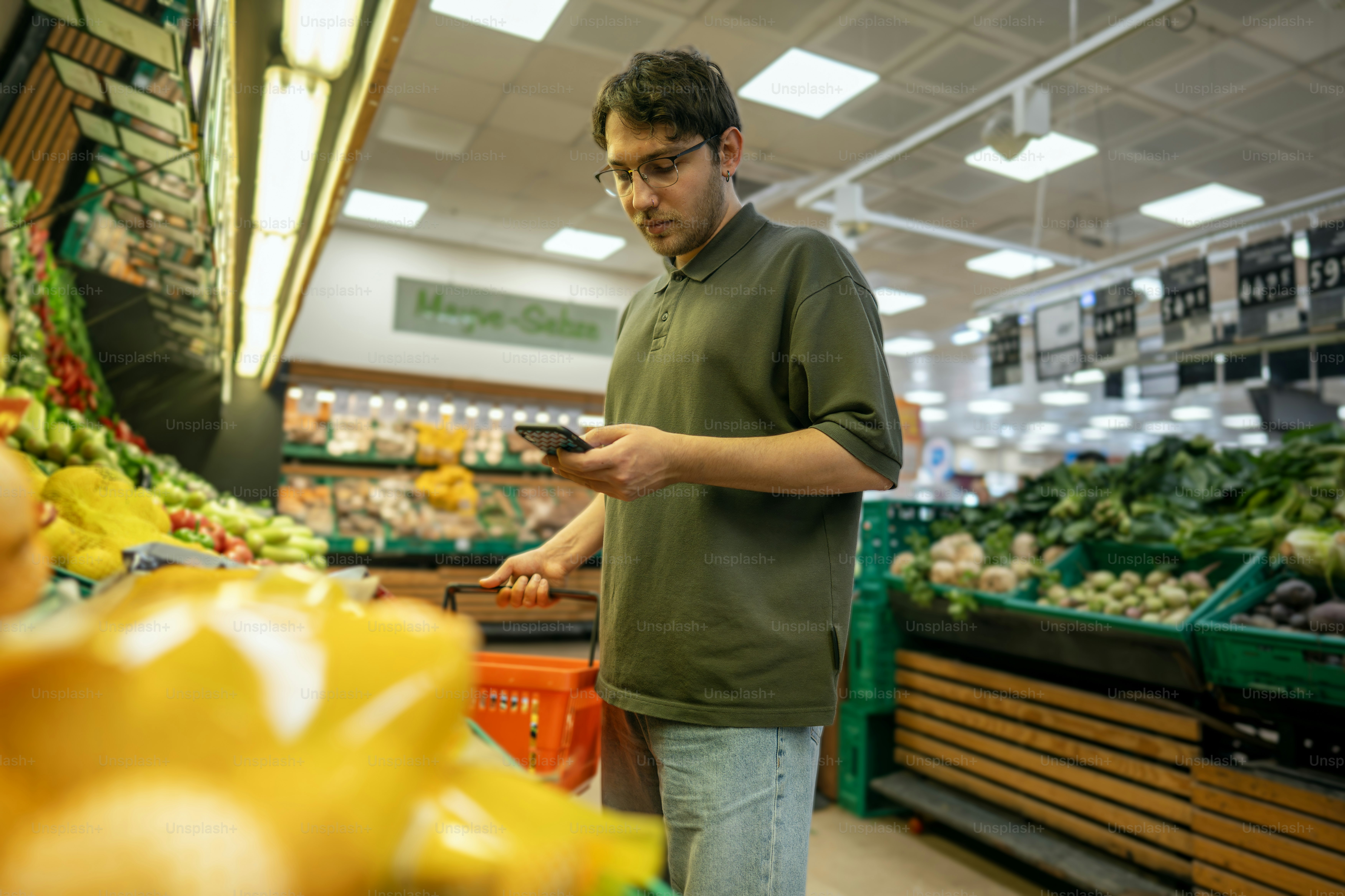 Man shops for groceries while looking at his phone.