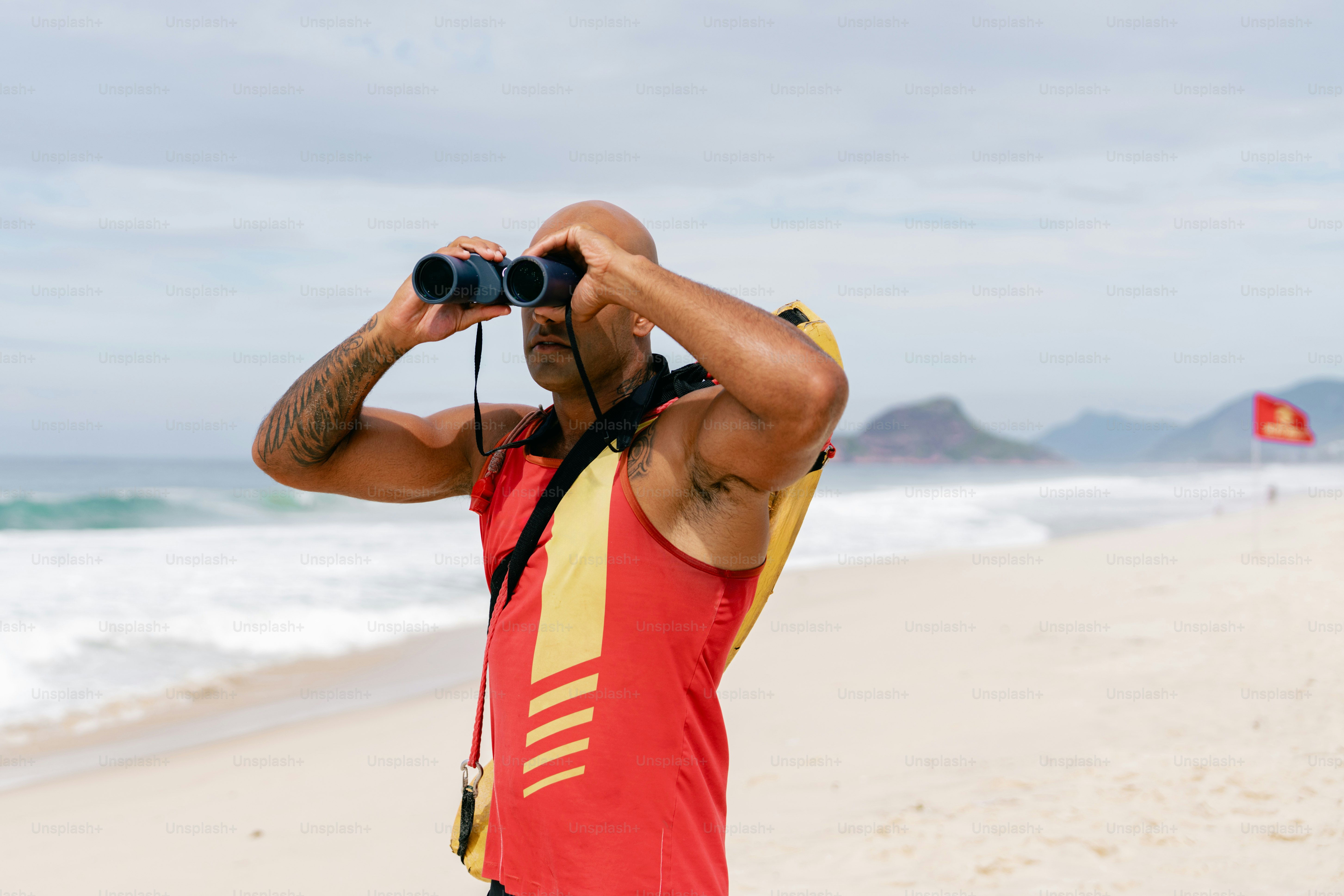 Lifeguard surveys the beach with binoculars.