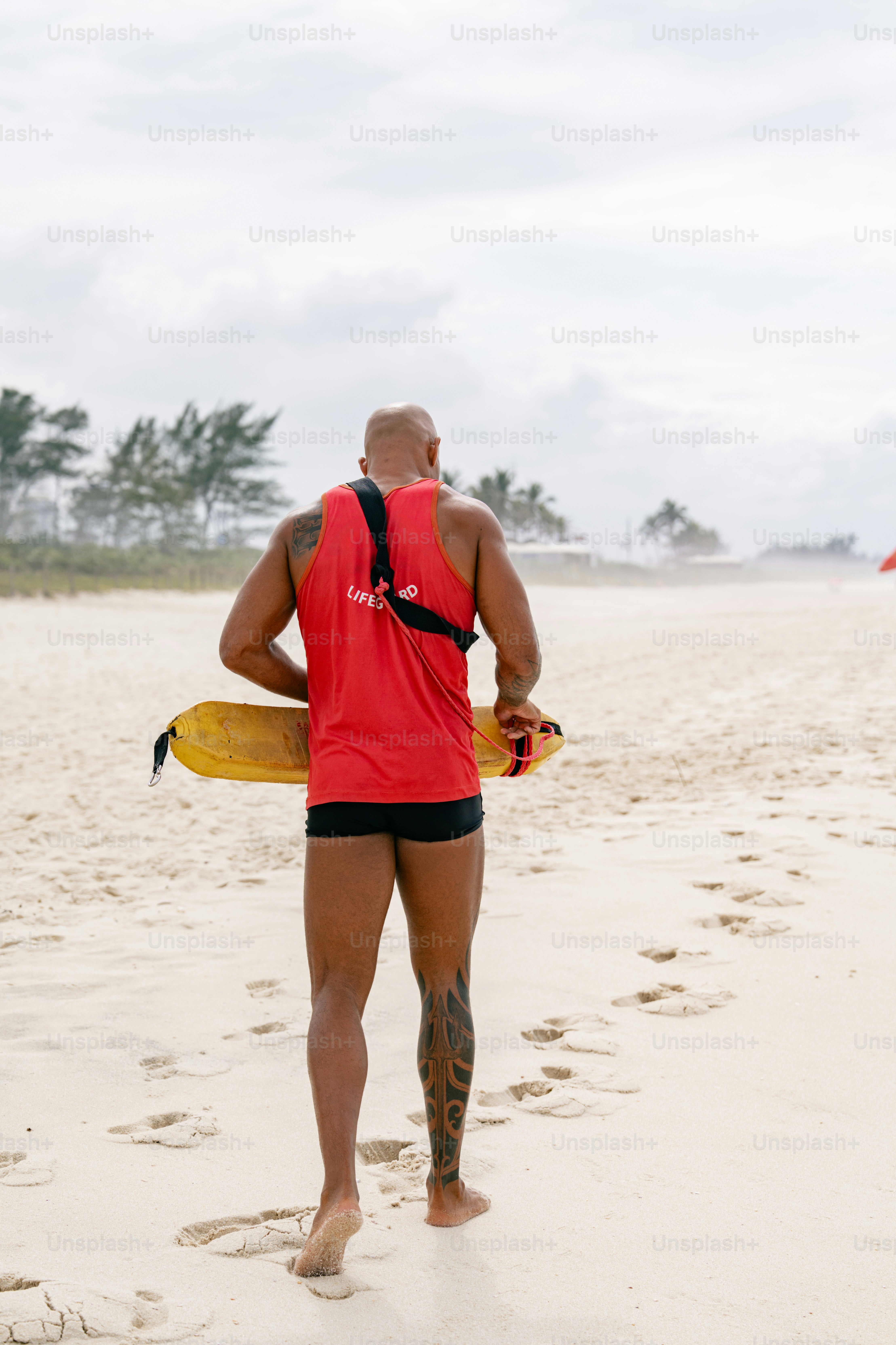 A lifeguard walks along the sandy beach.