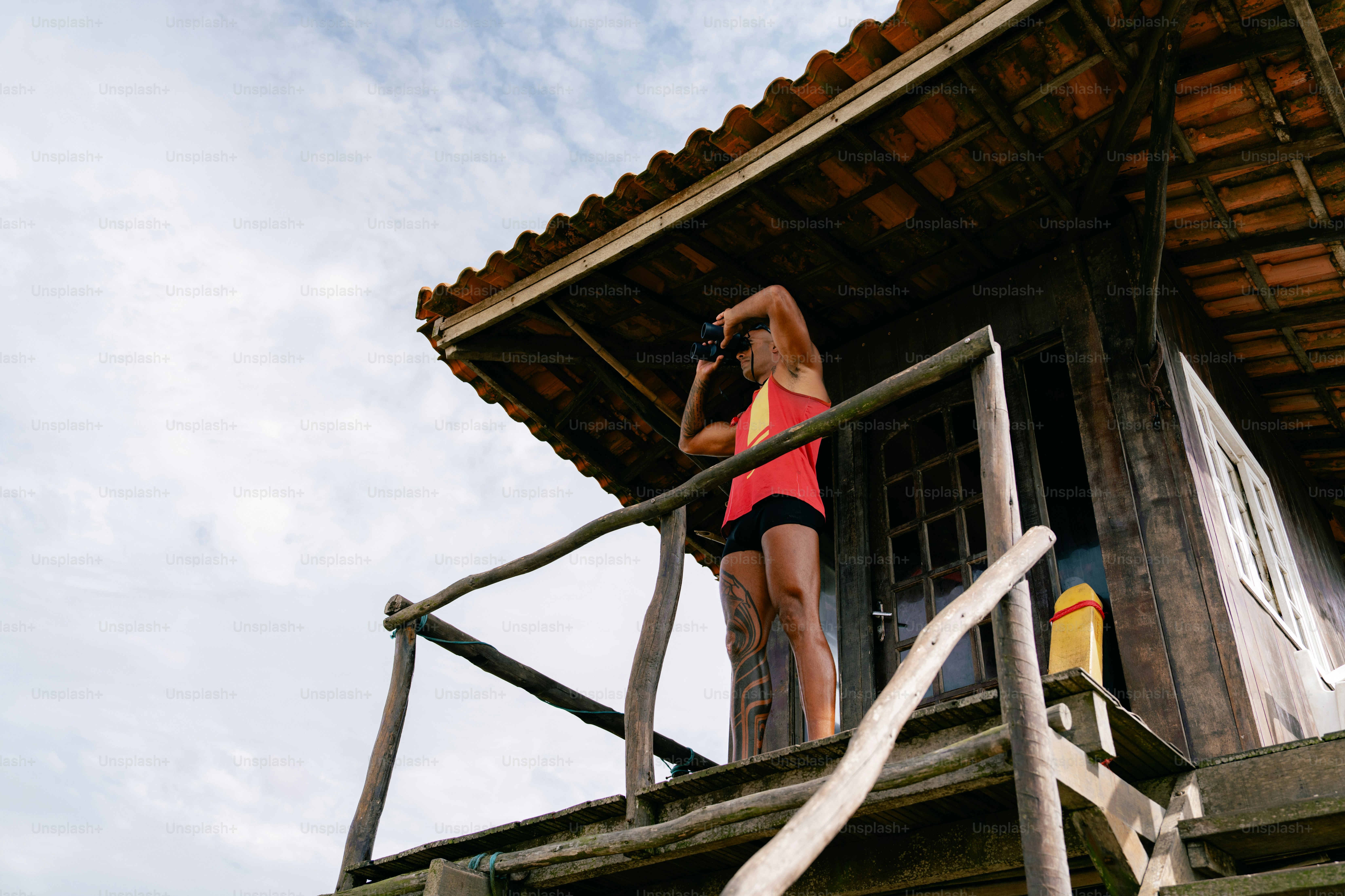 Woman takes pictures from a wooden building's porch.