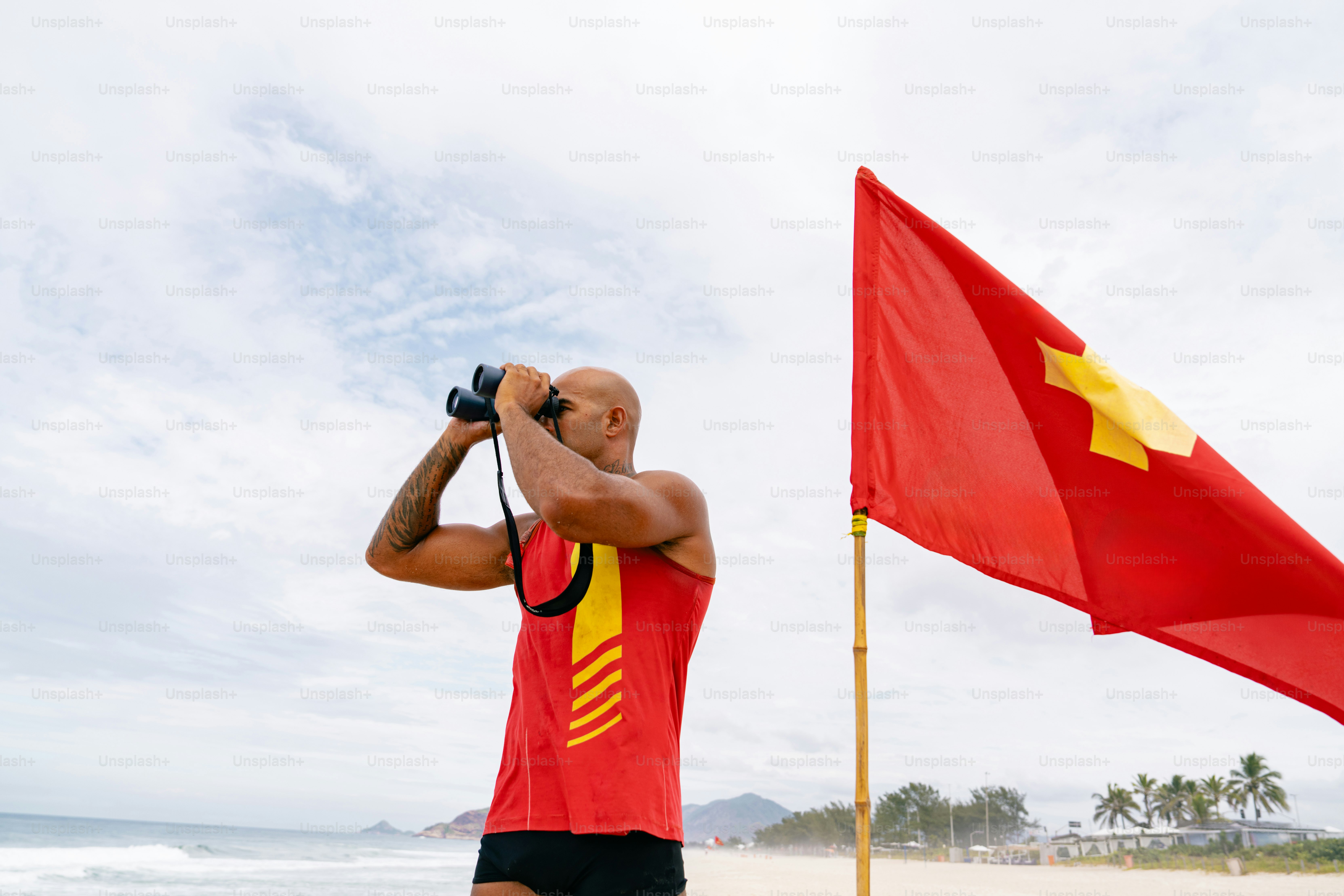 Lifeguard scans the sea with binoculars.