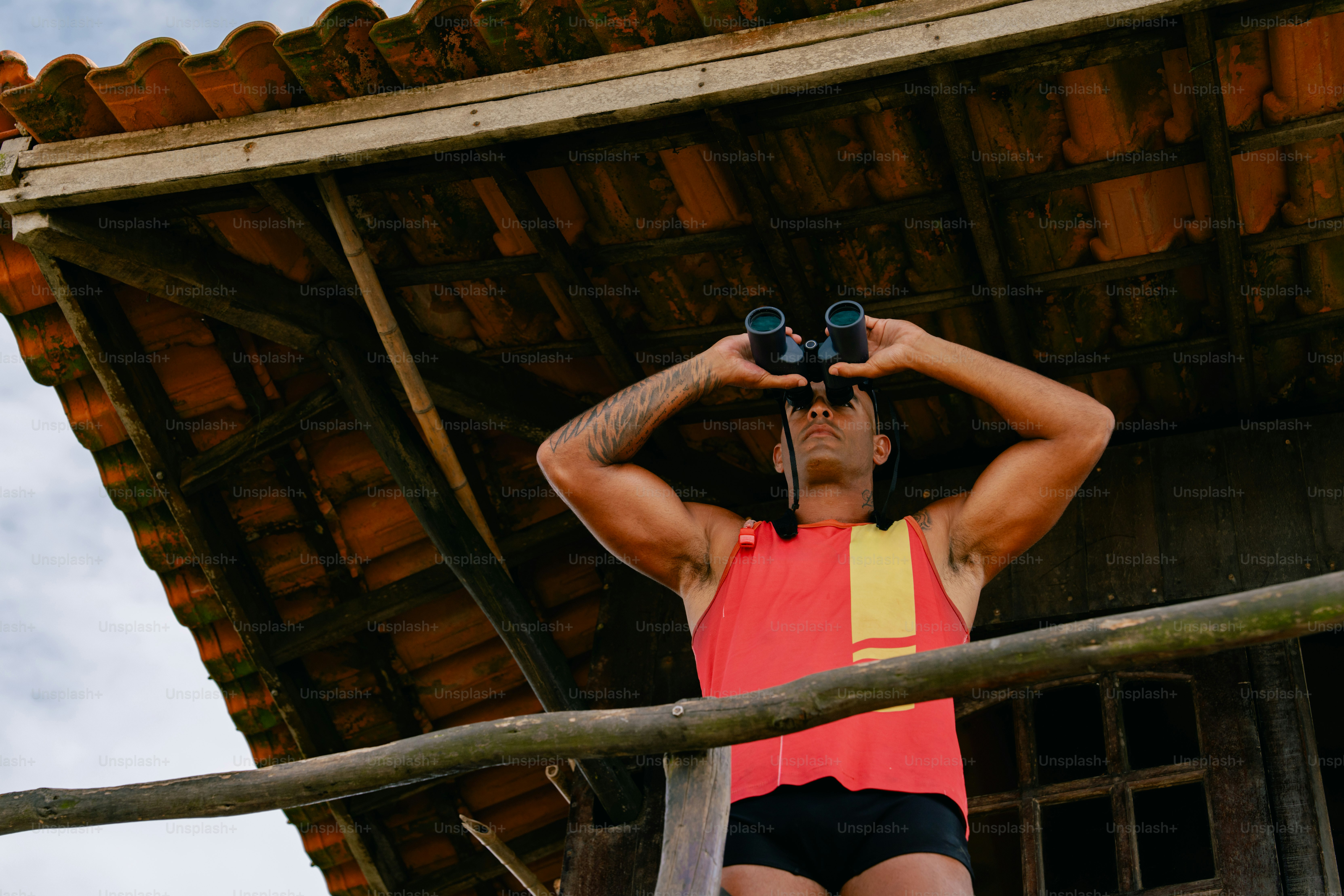 Lifeguard watches the ocean with binoculars from his post.