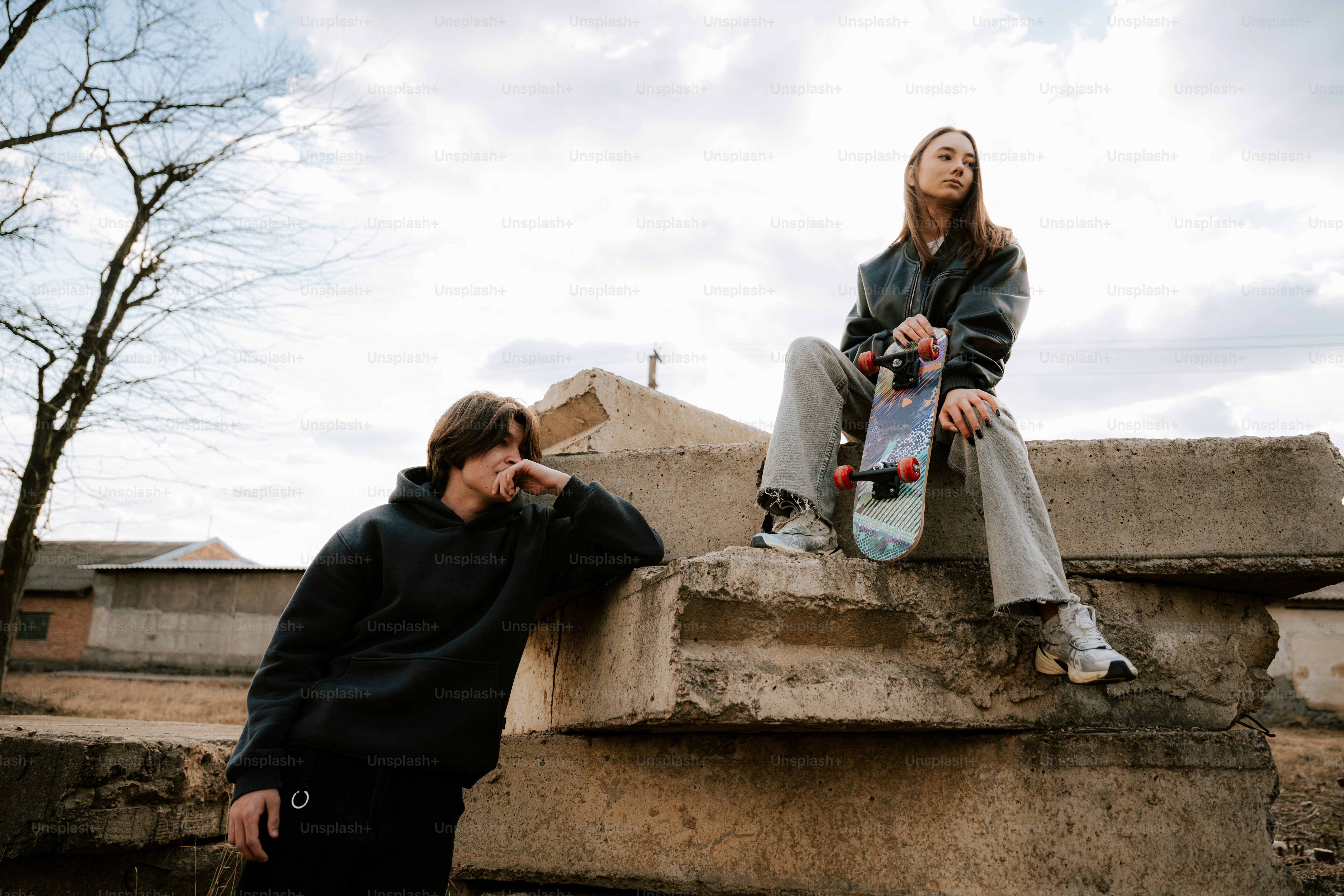 Two young people posing with a skateboard.