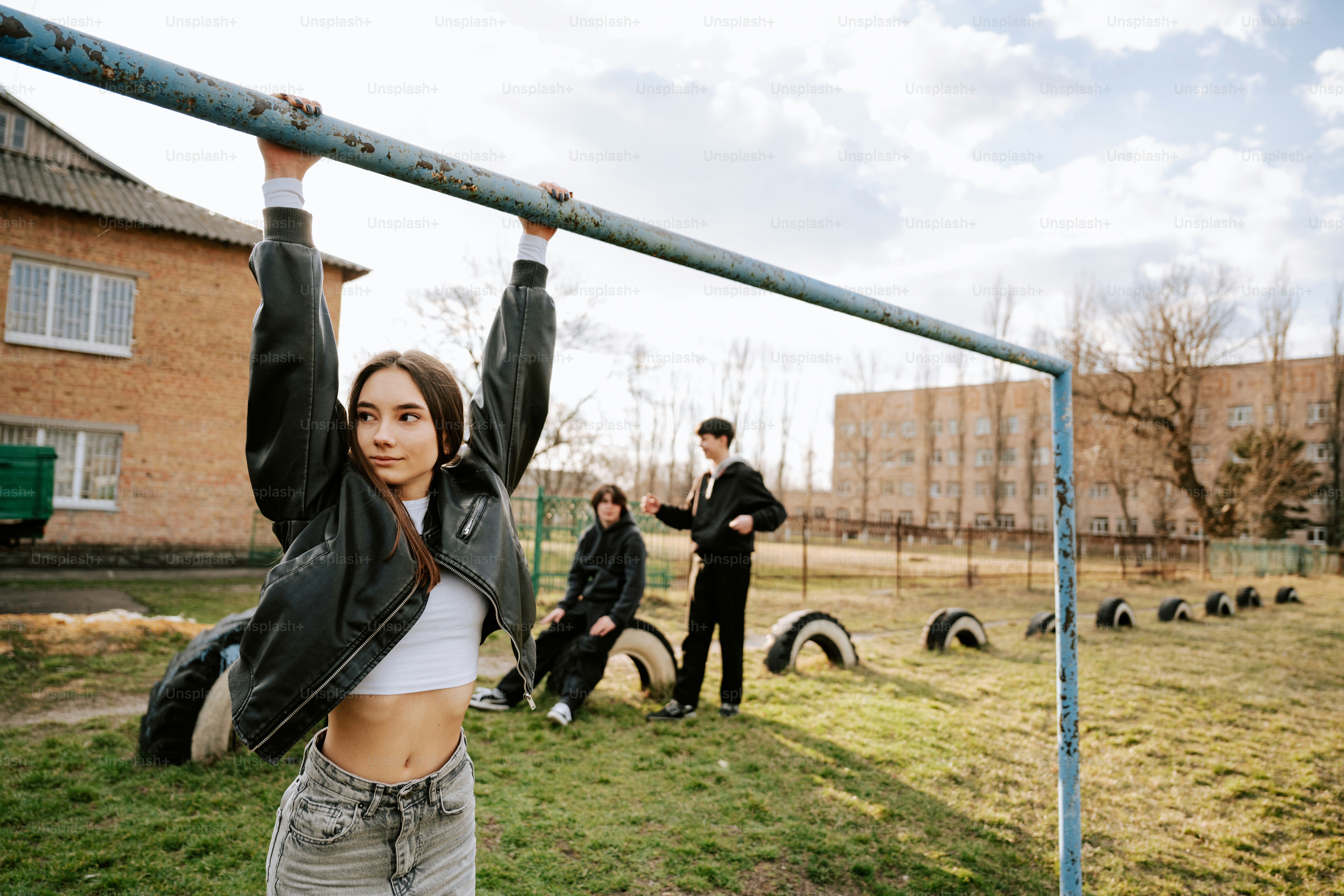Una mujer joven cuelga de una barra horizontal.