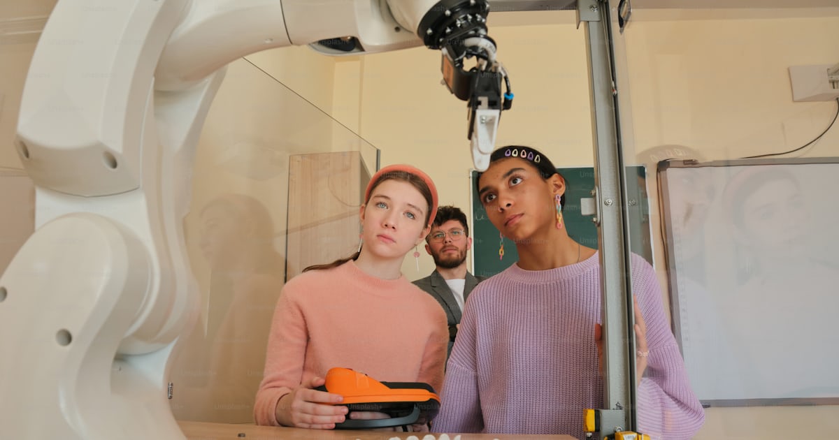 Students observe a robot arm in a lab. photo – Technology Image on Unsplash
