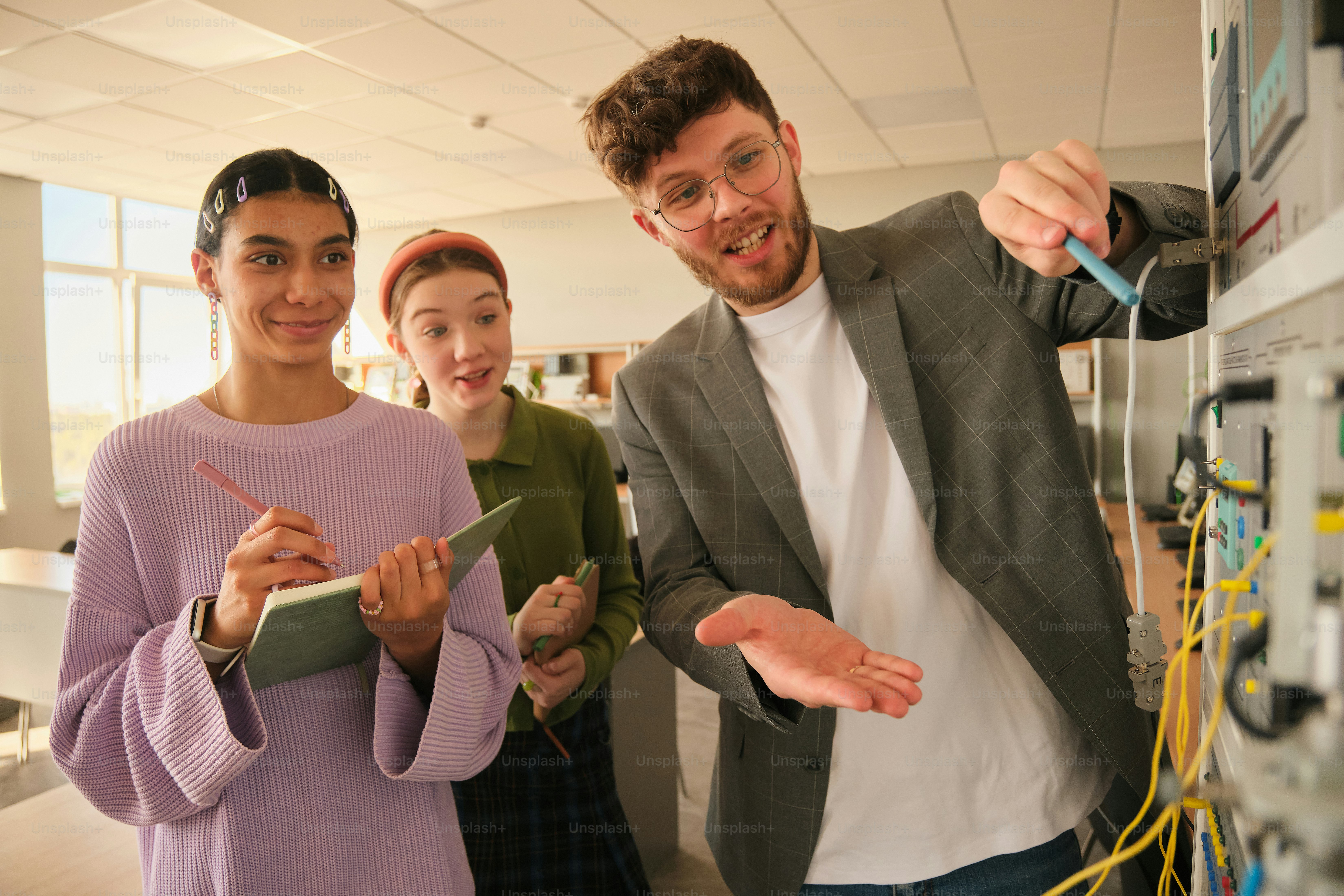 Students are studying a machine with their professor. photo ...