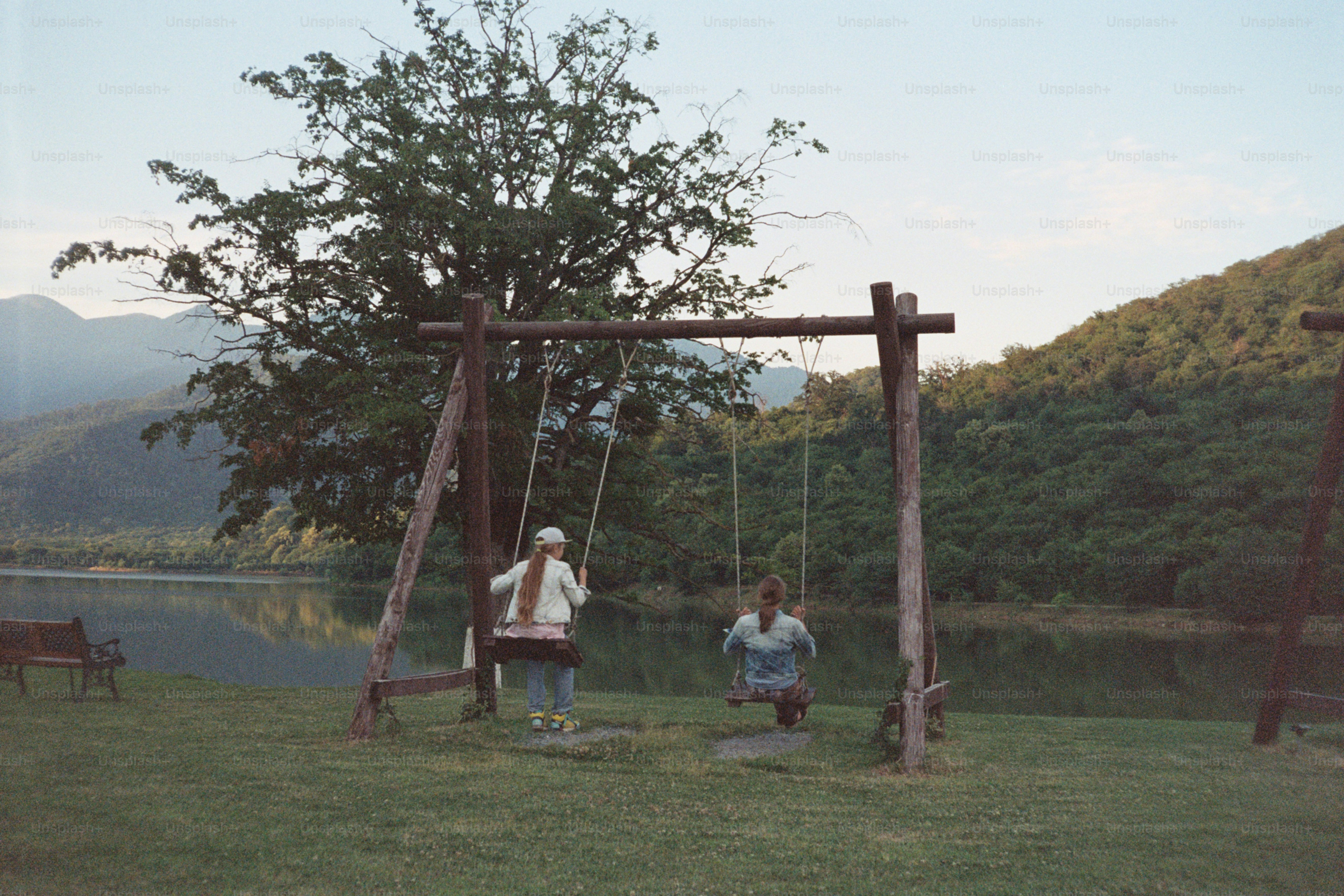 Two people swing by a lake.