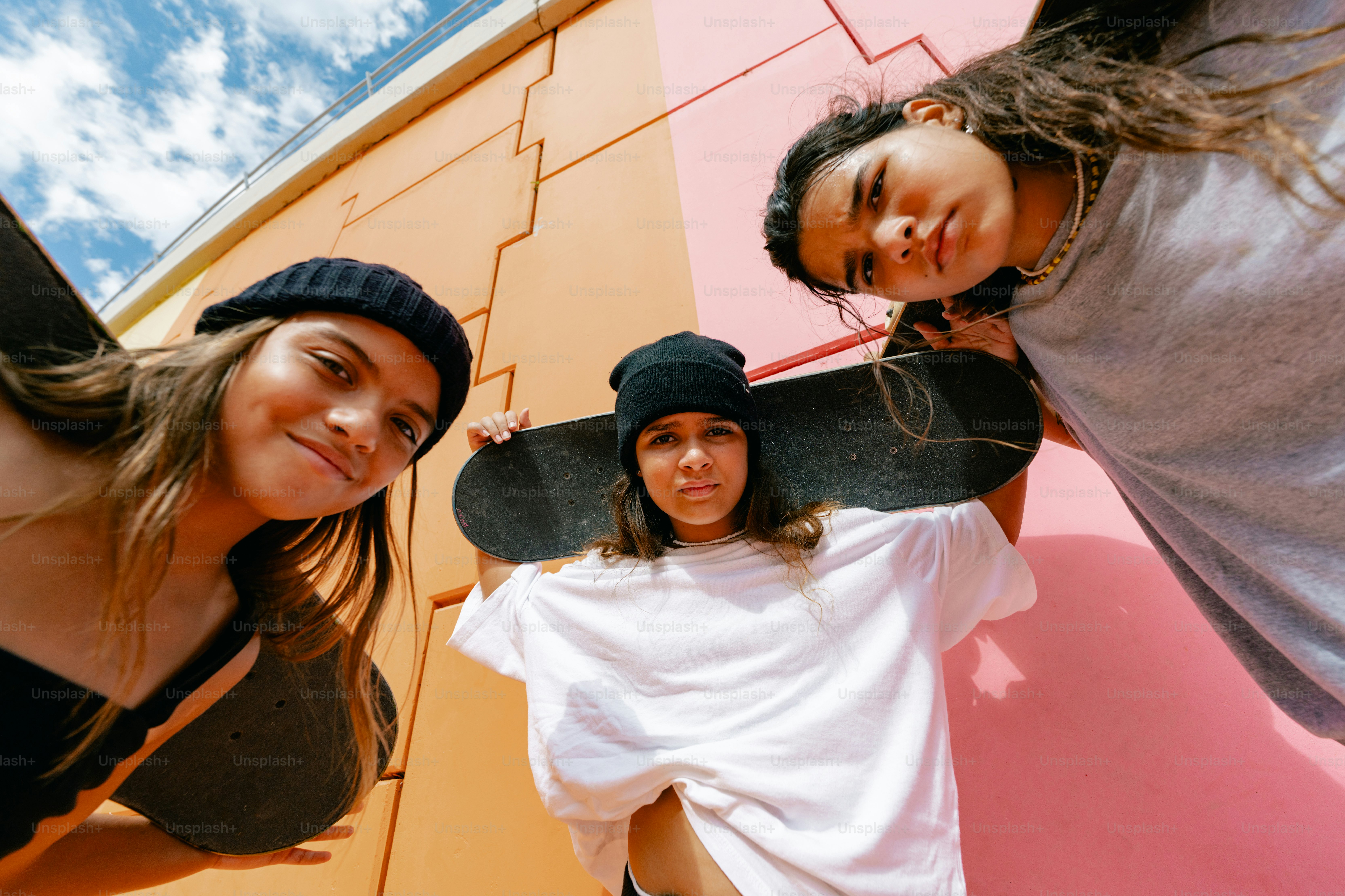 Three young people pose with skateboards.