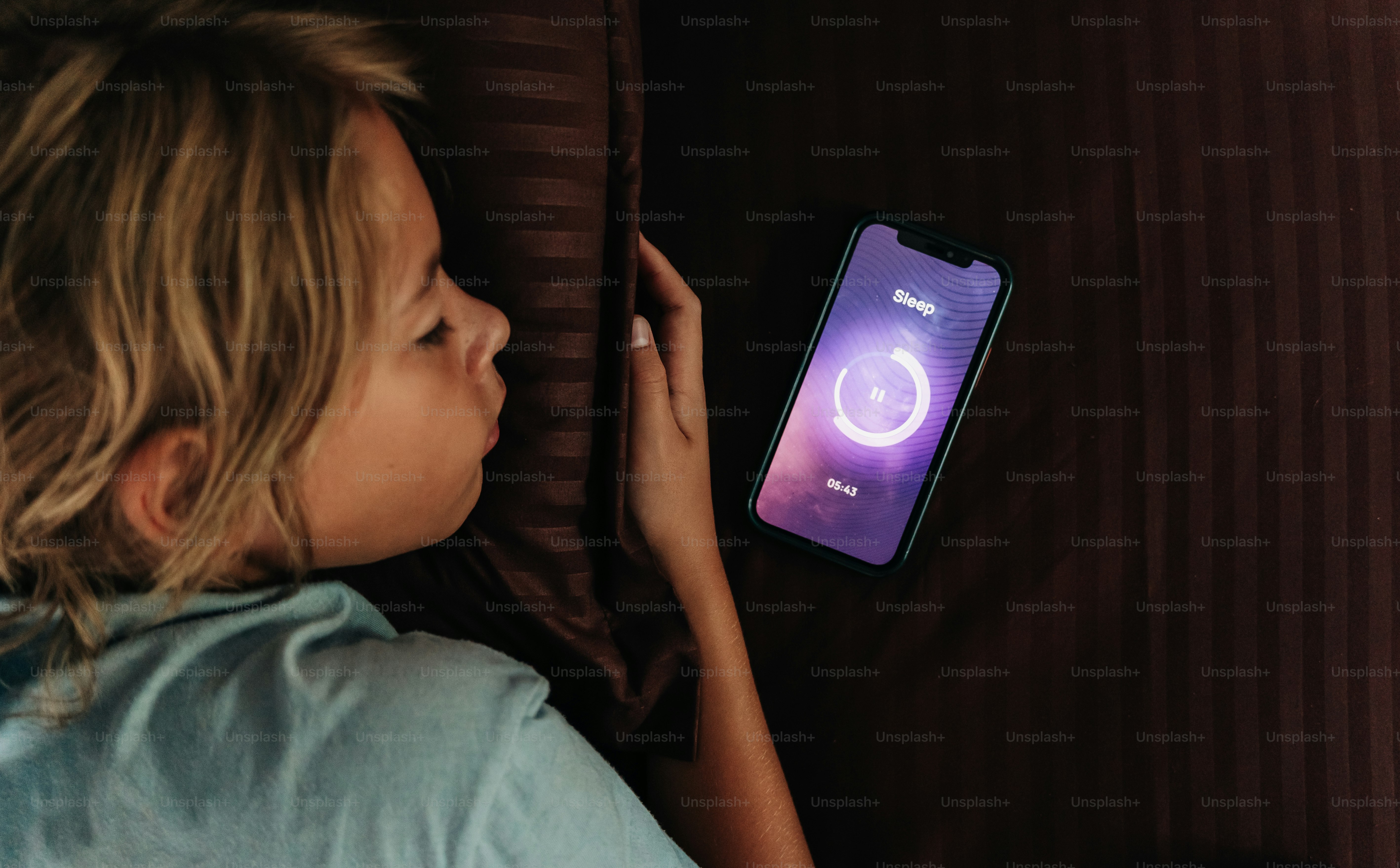 A sleeping child has a phone displaying a ring.