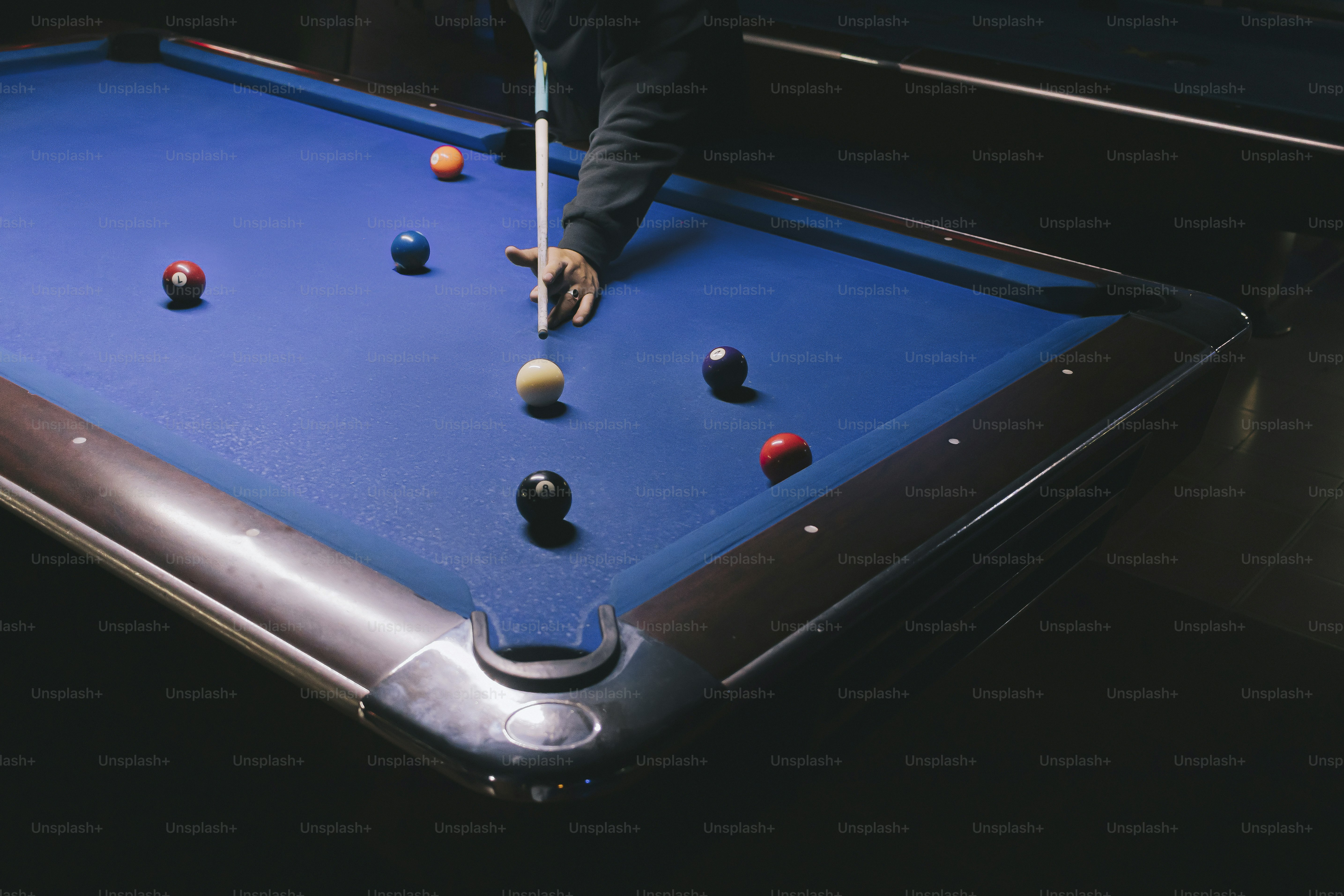 Person playing pool, cue stick at the ready.