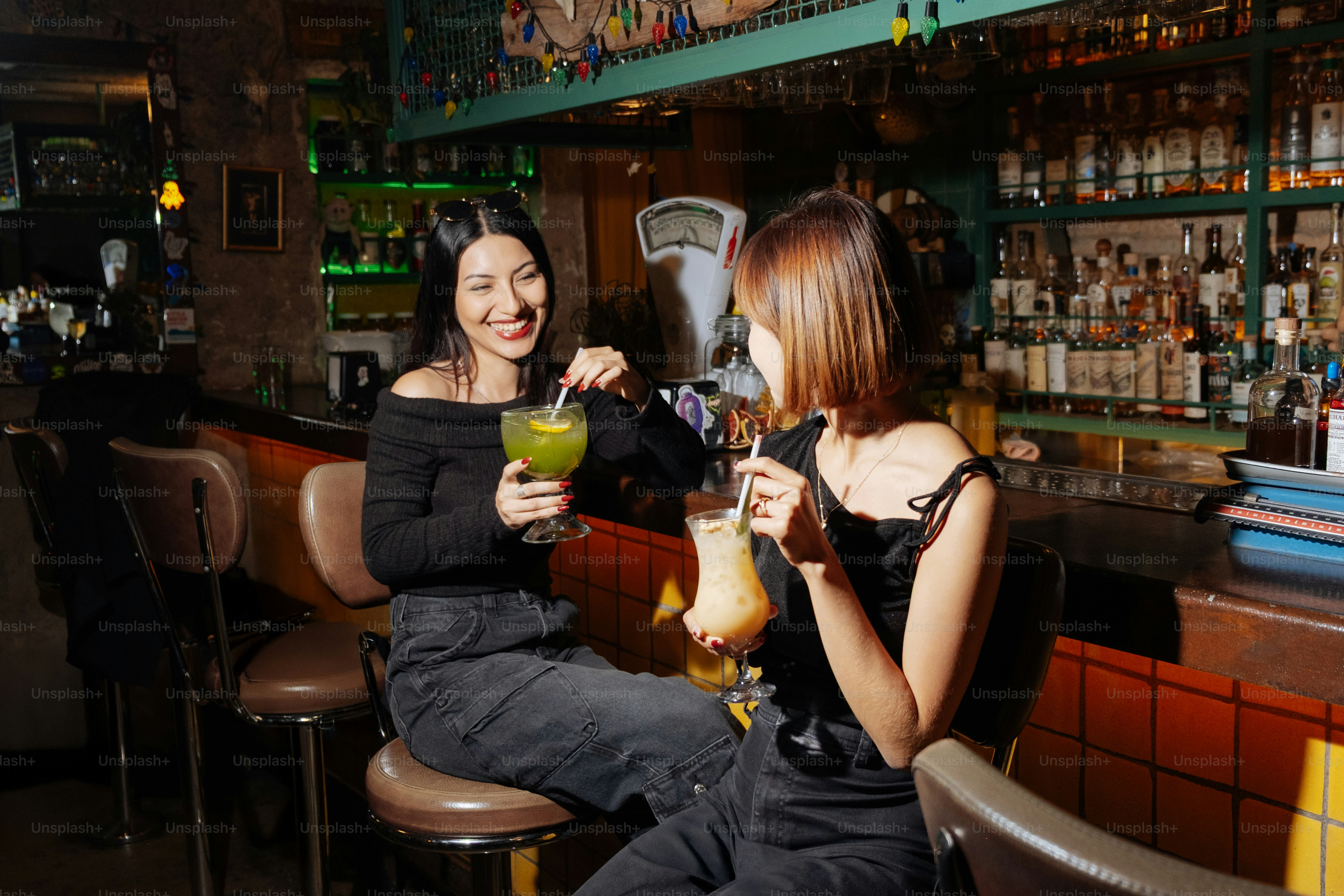 Two women enjoy drinks at a bar.