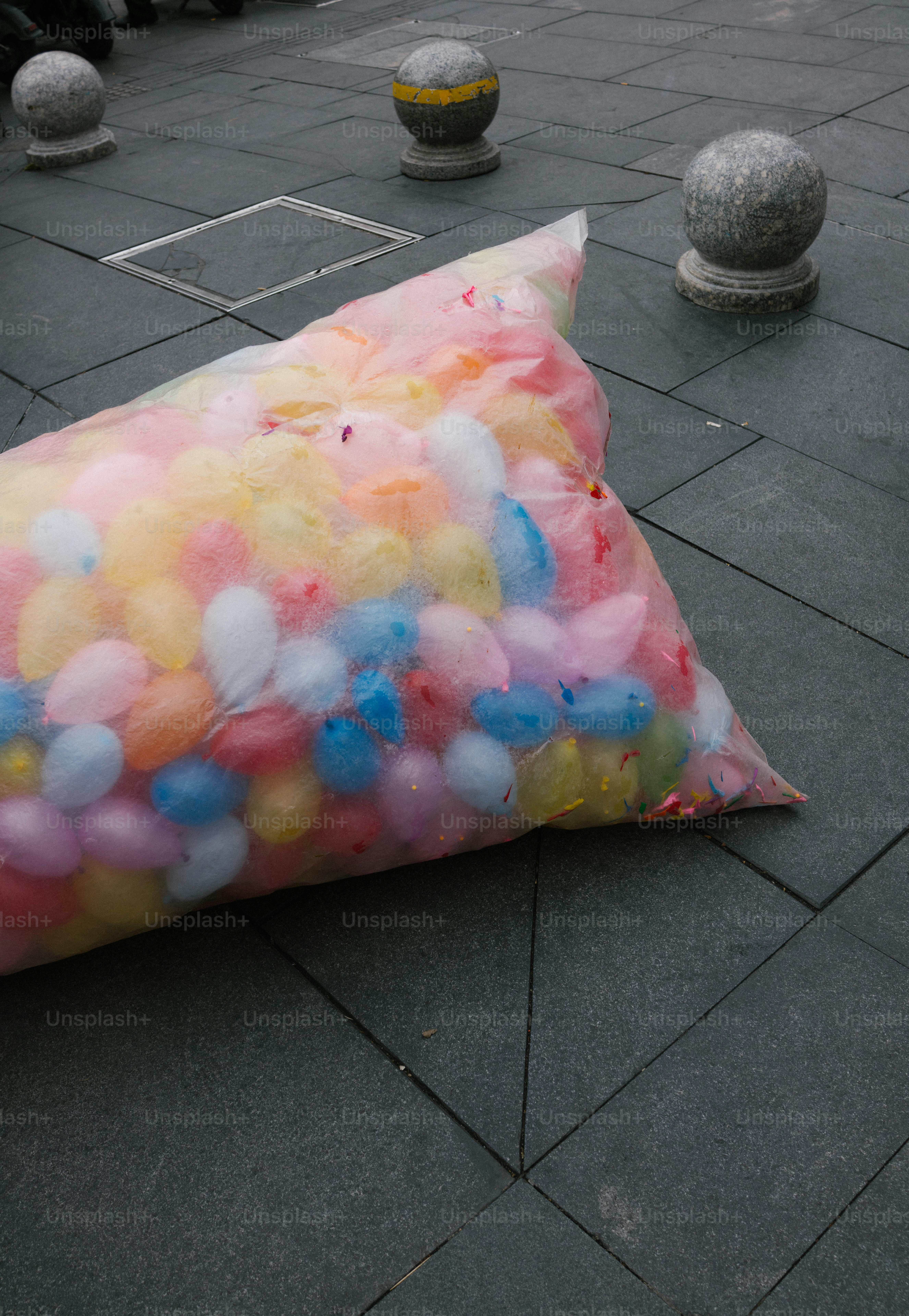 A bag of colorful water balloons rests on pavement
