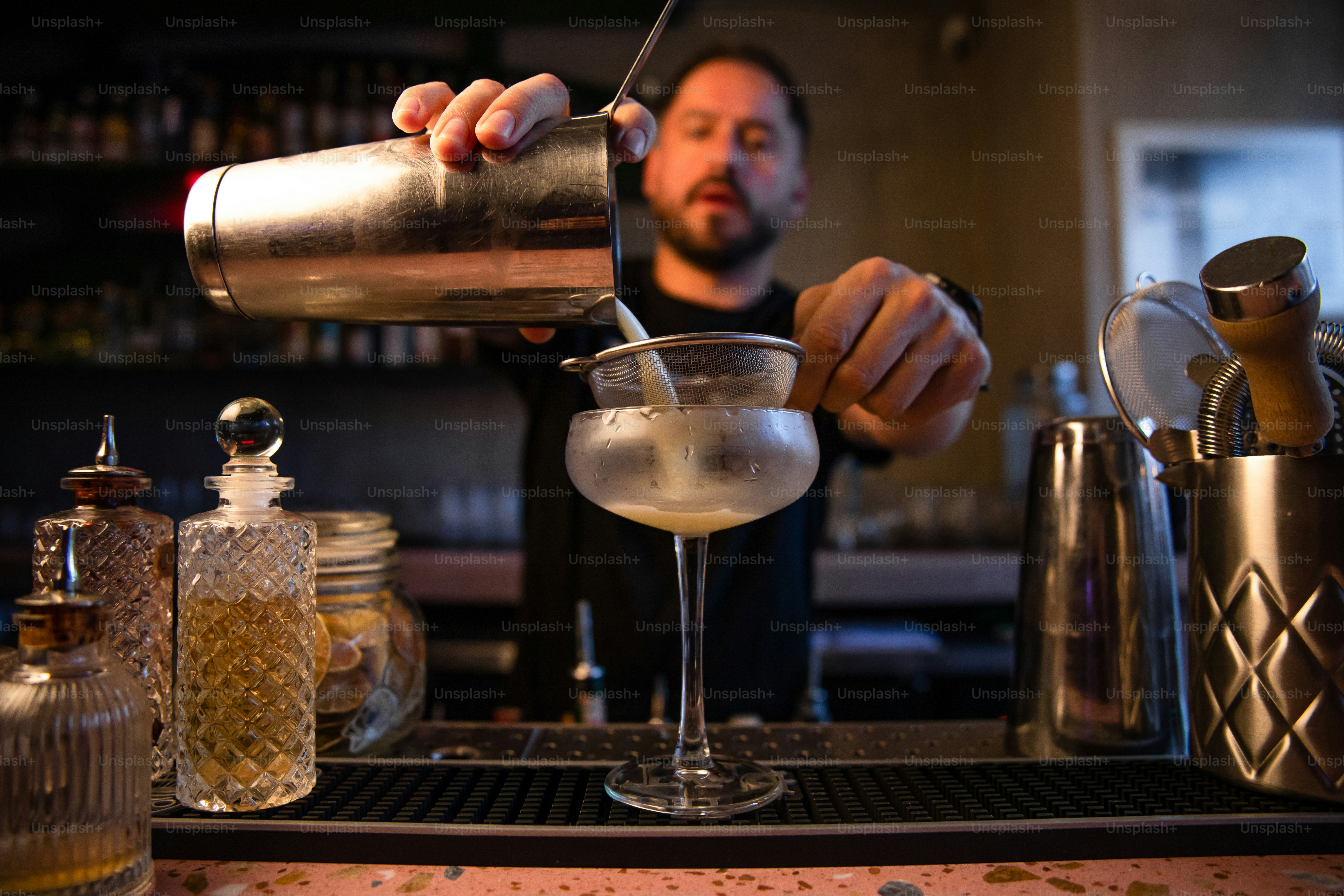 Bartender menuangkan minuman ke dalam gelas koktail.