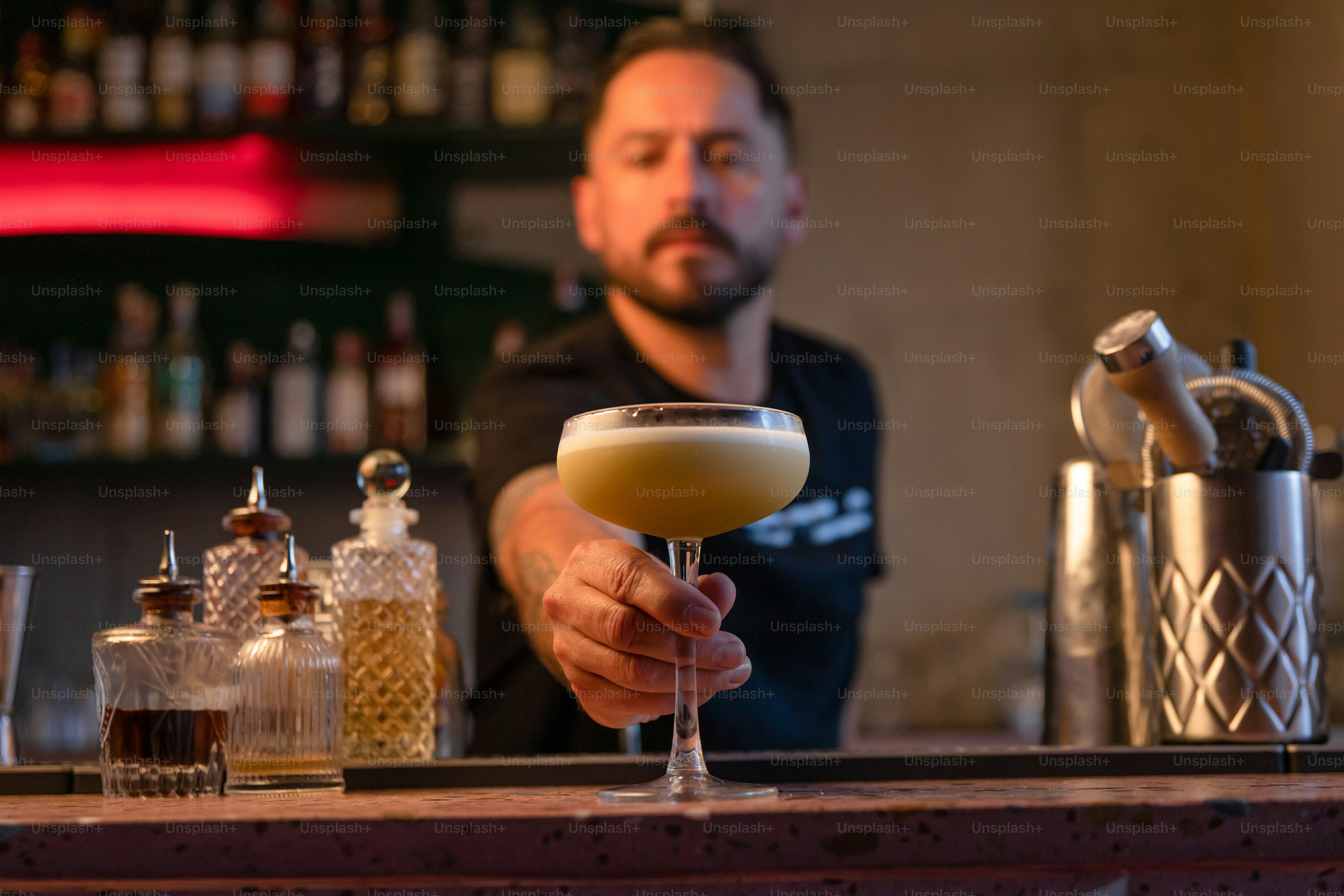 A bartender is presenting a cocktail to the viewer.