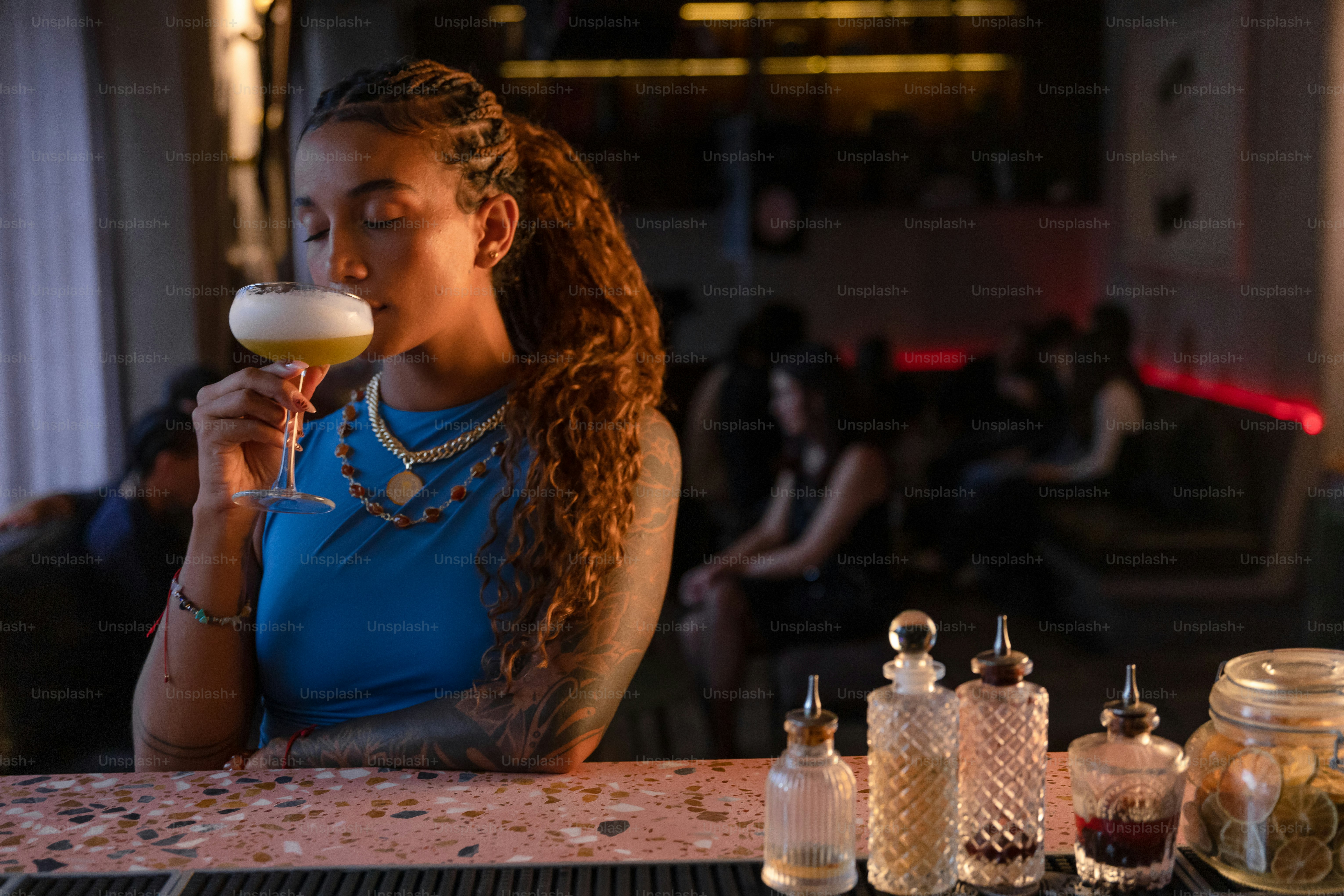 Woman sips a cocktail in a dimly lit bar.
