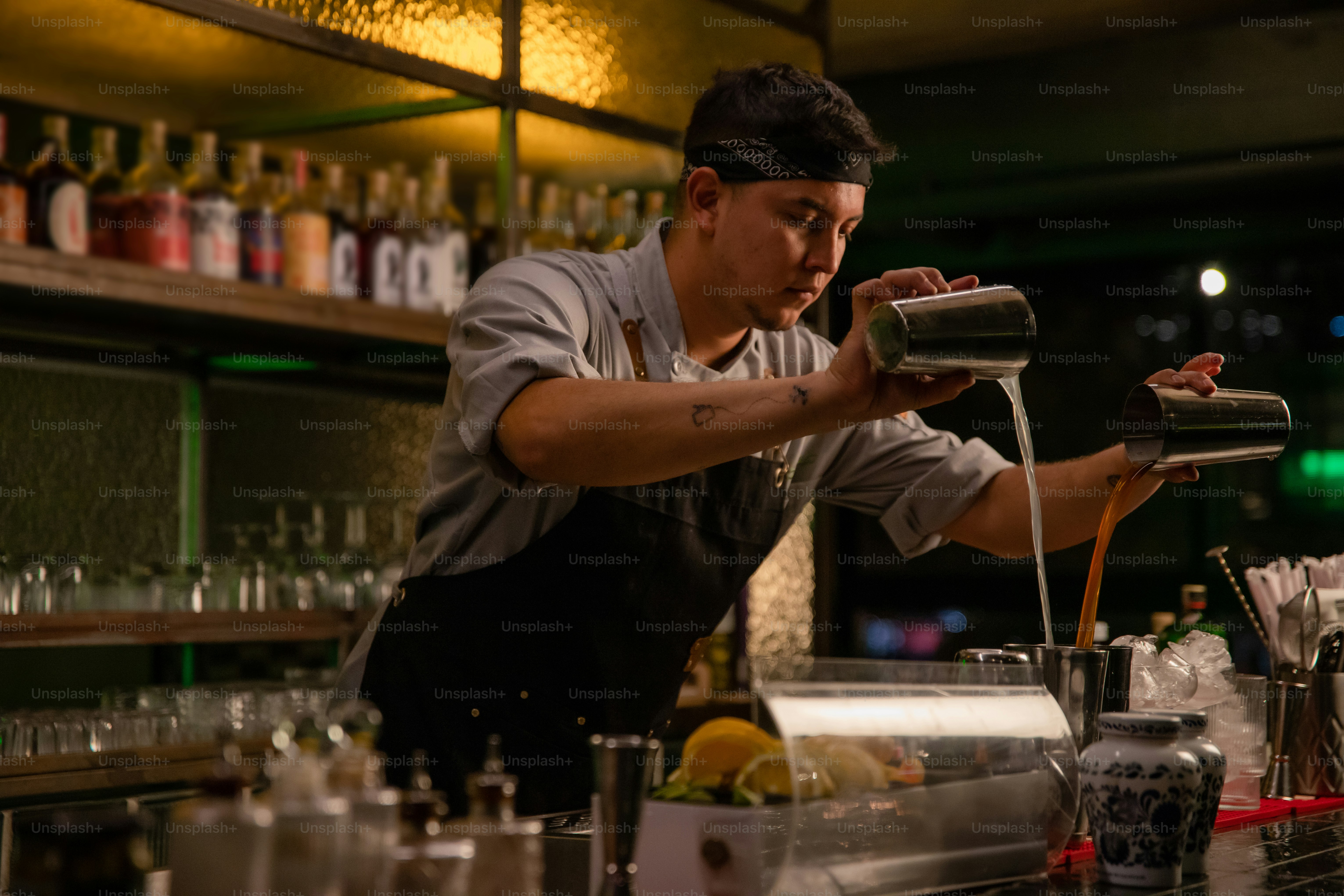 Seorang bartender dengan ahli menuangkan minuman campuran.