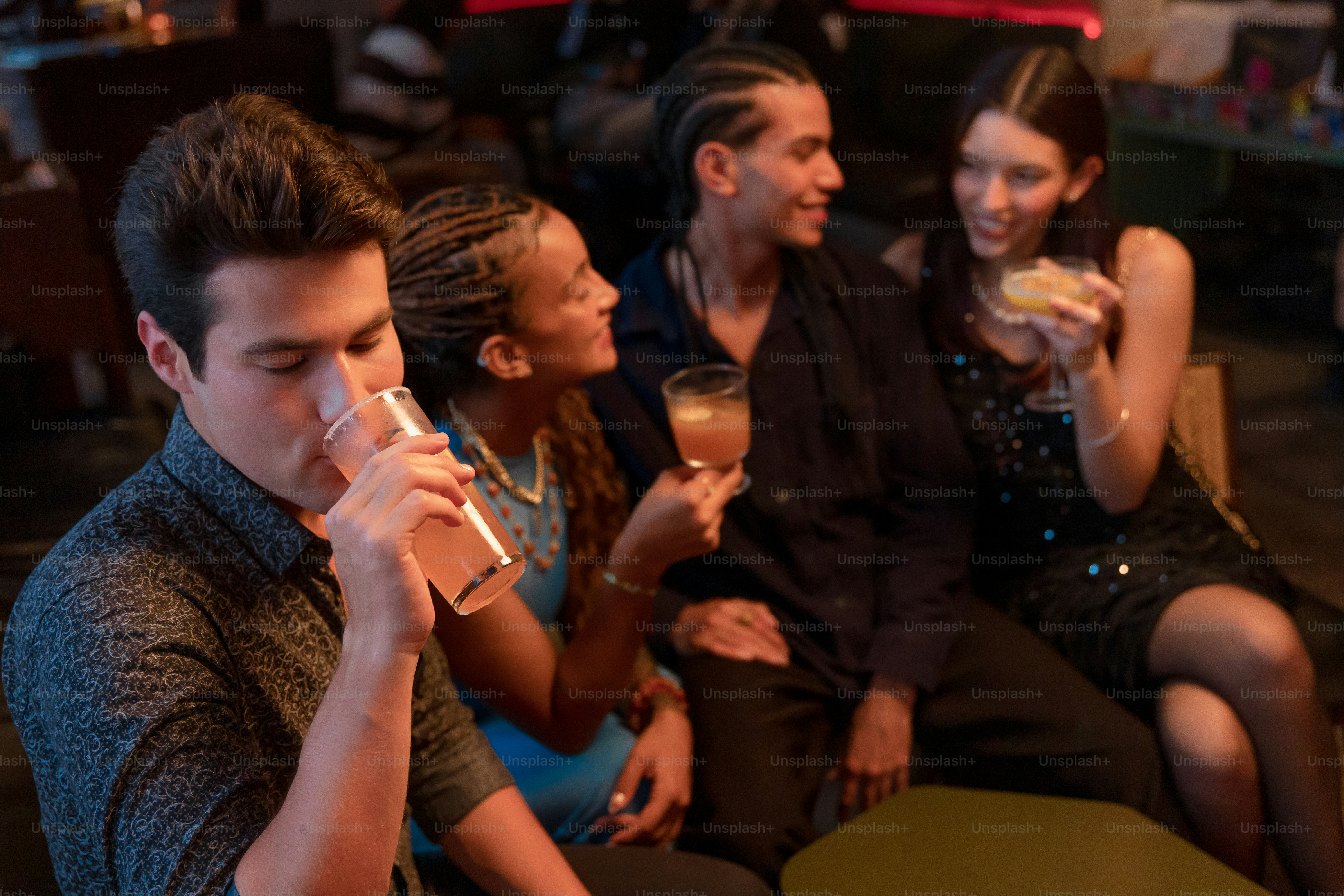 Friends socialize and drink cocktails at a bar.