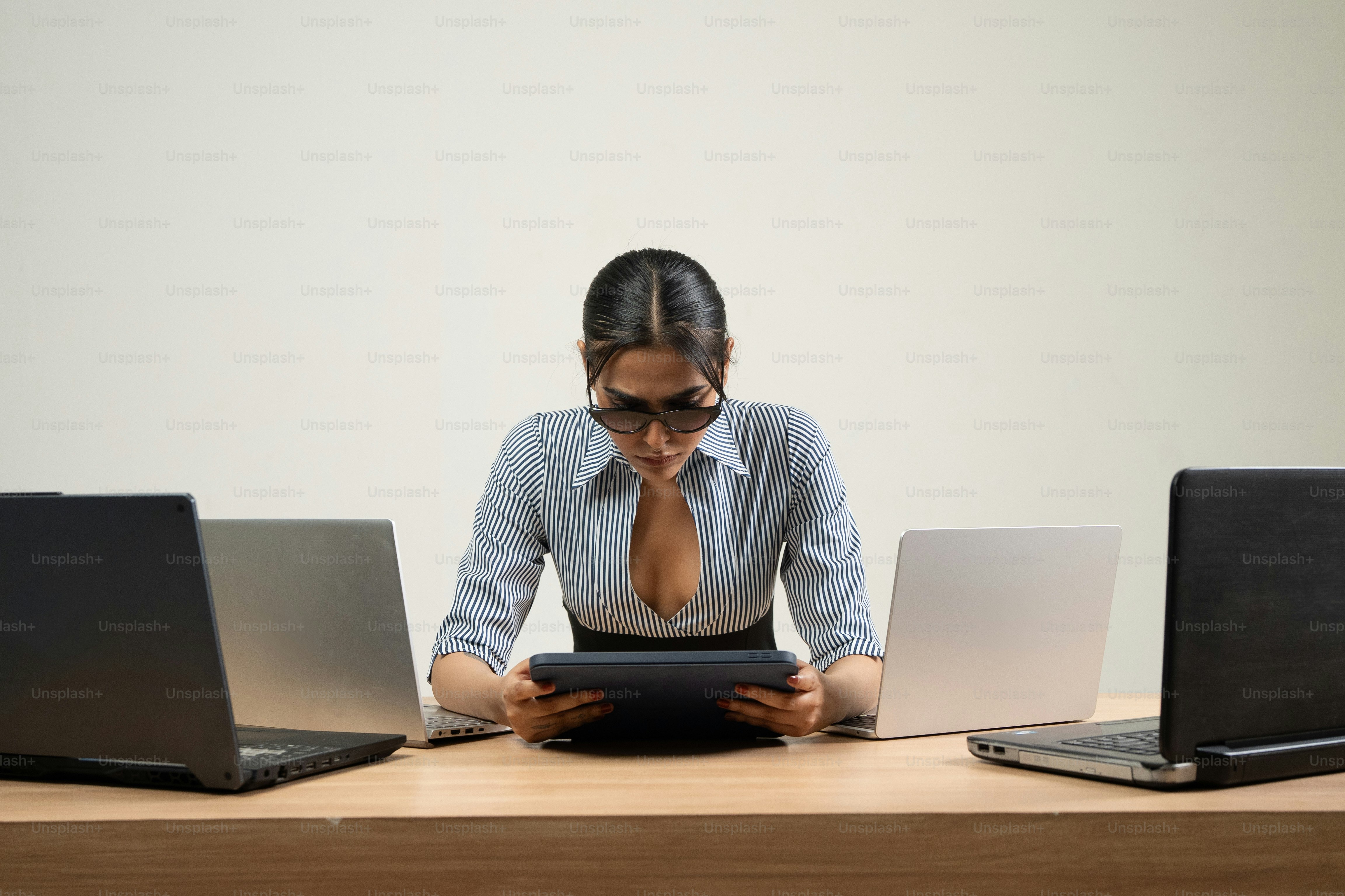 La empresaria trabaja en una tableta rodeada de computadoras portátiles.