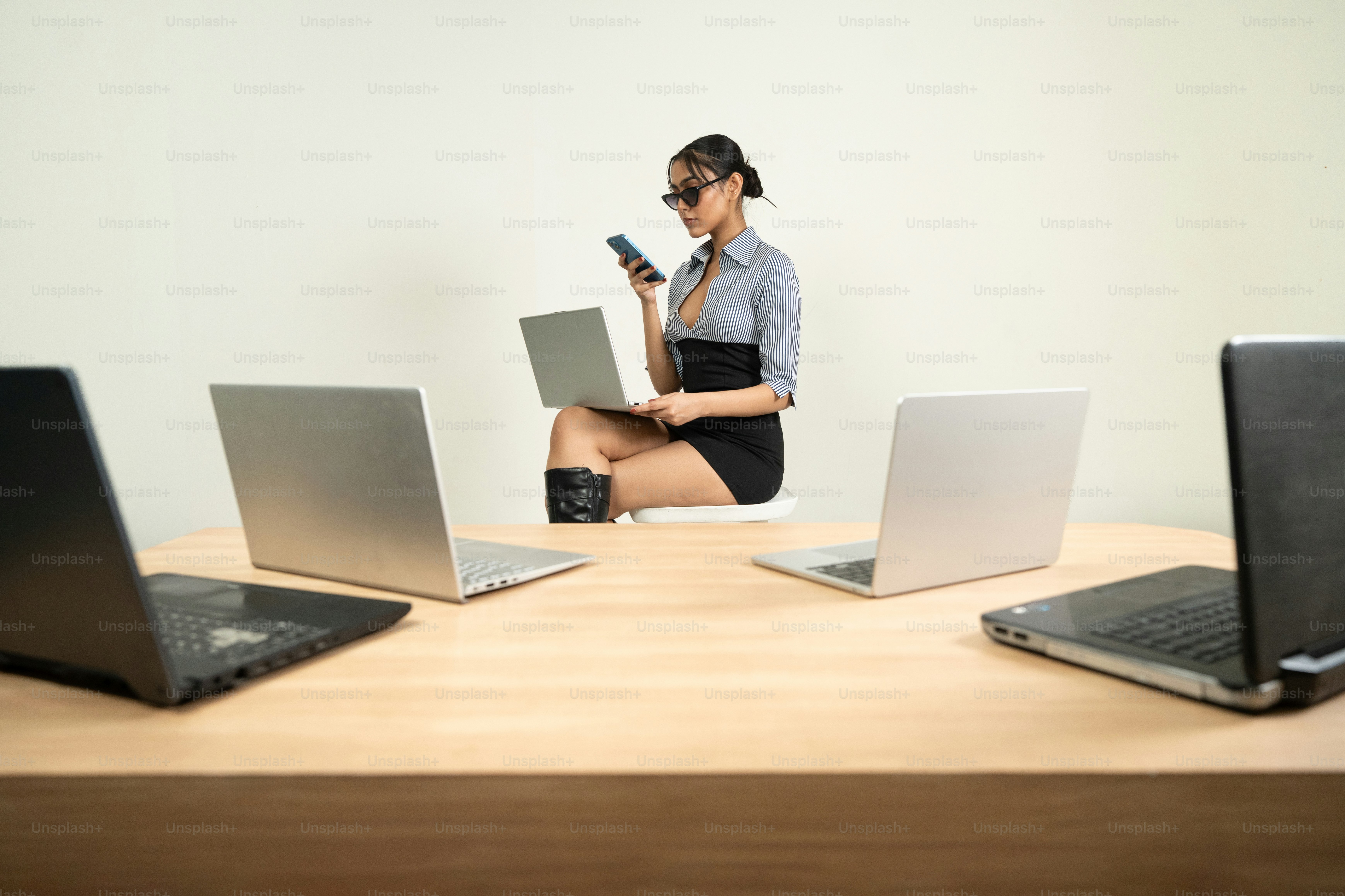 La mujer trabaja con computadoras portátiles y un teléfono.