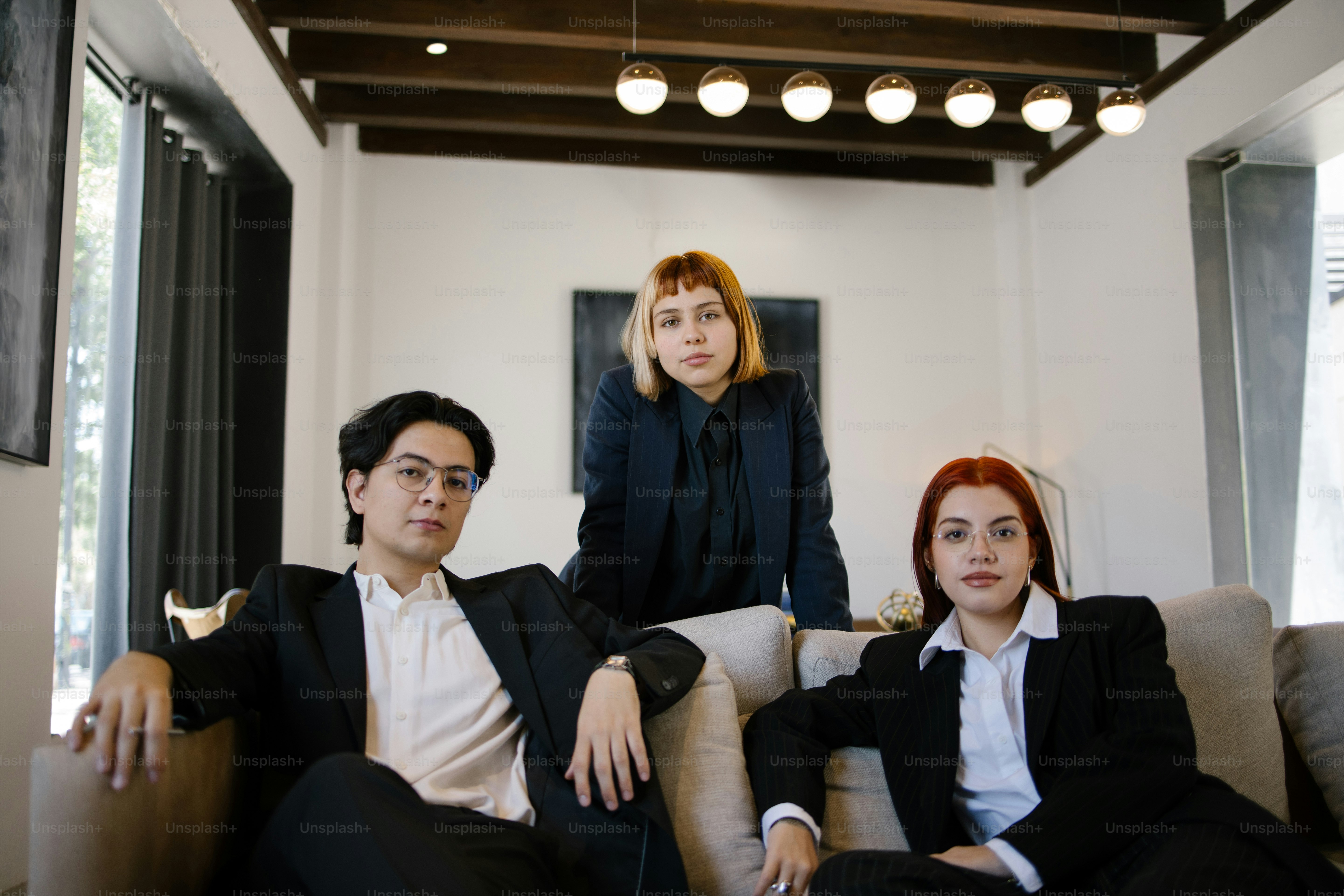 Three people pose confidently in formal attire.