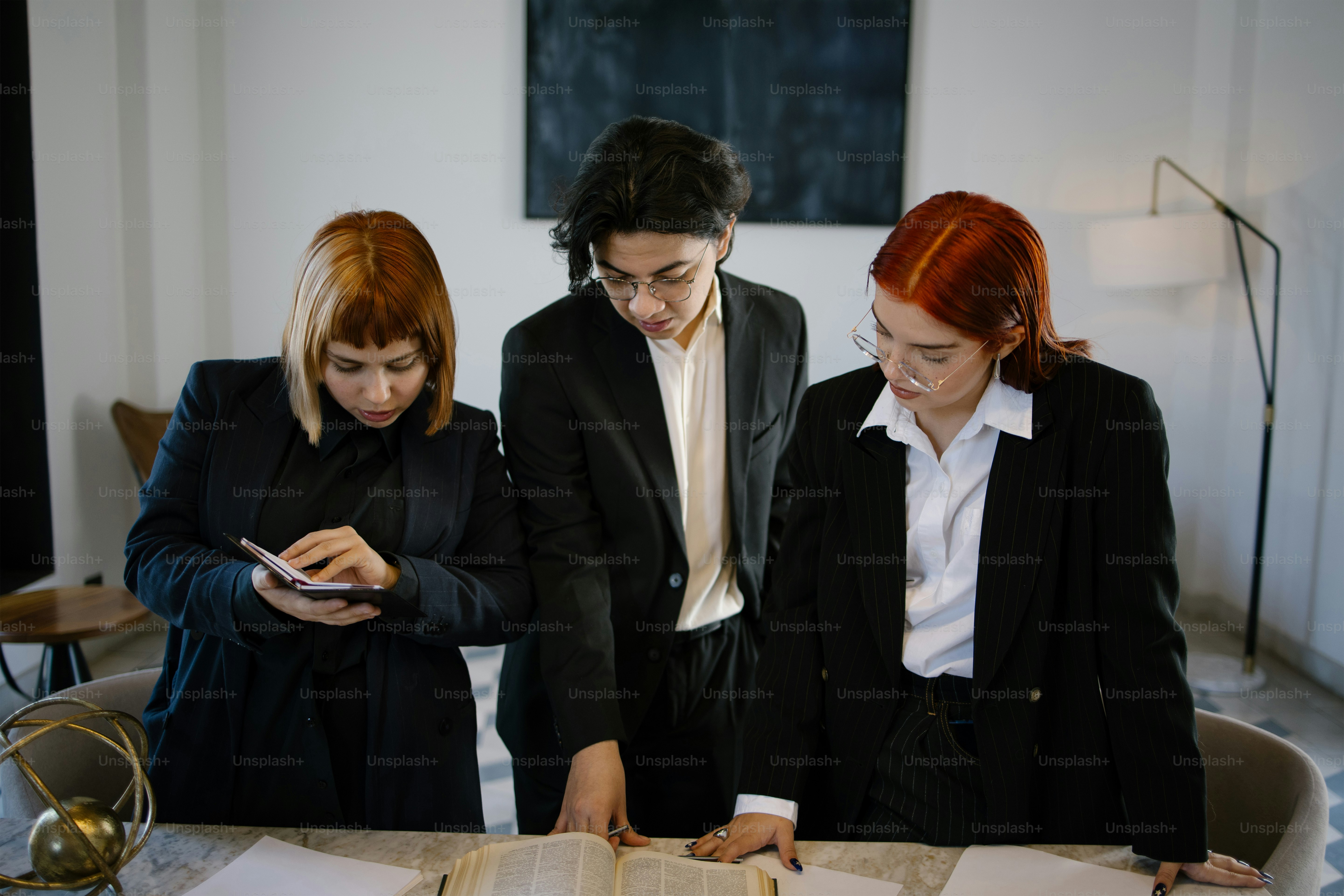 Three people in suits review documents.