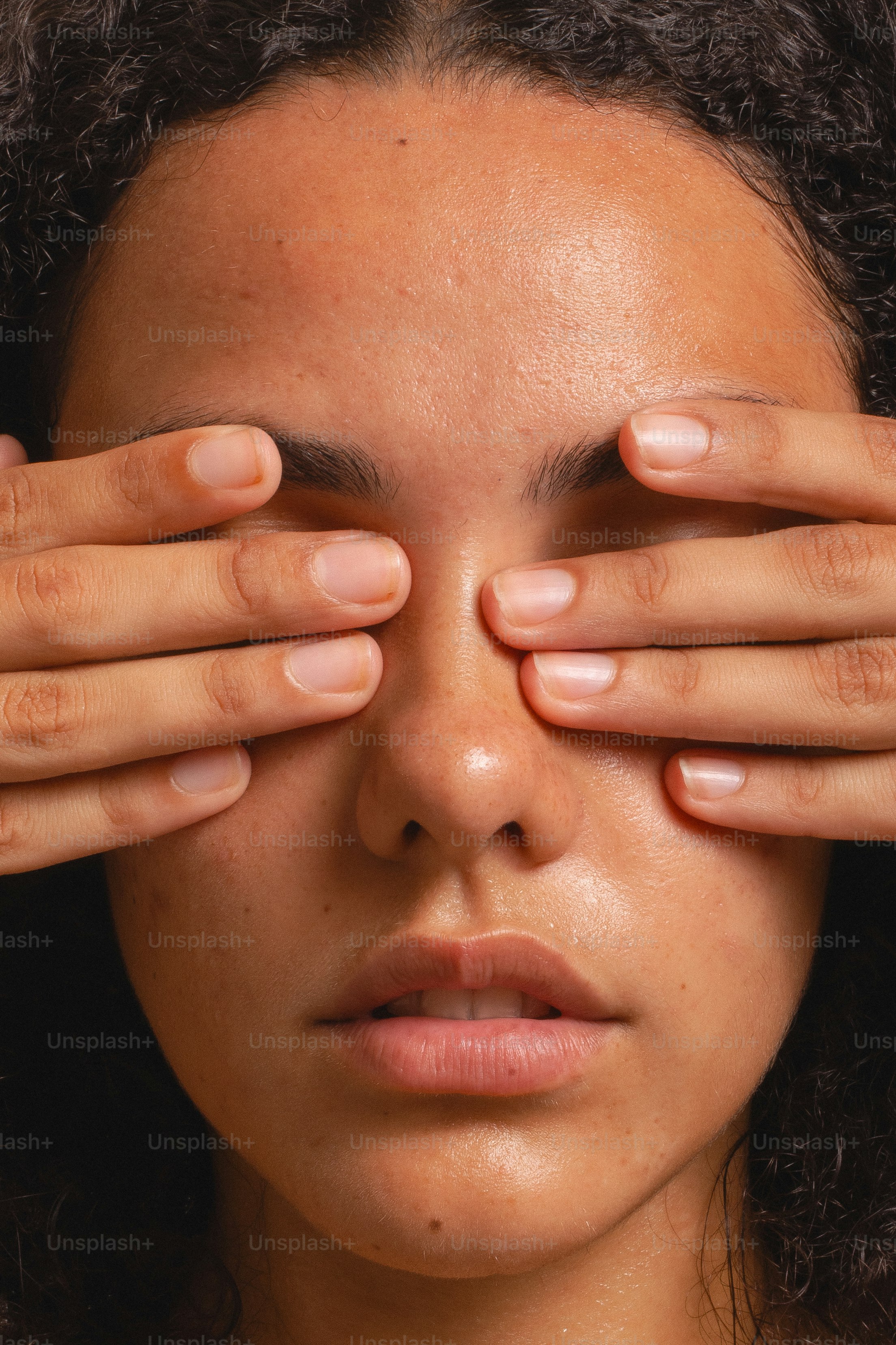 Woman covers her eyes with both hands.