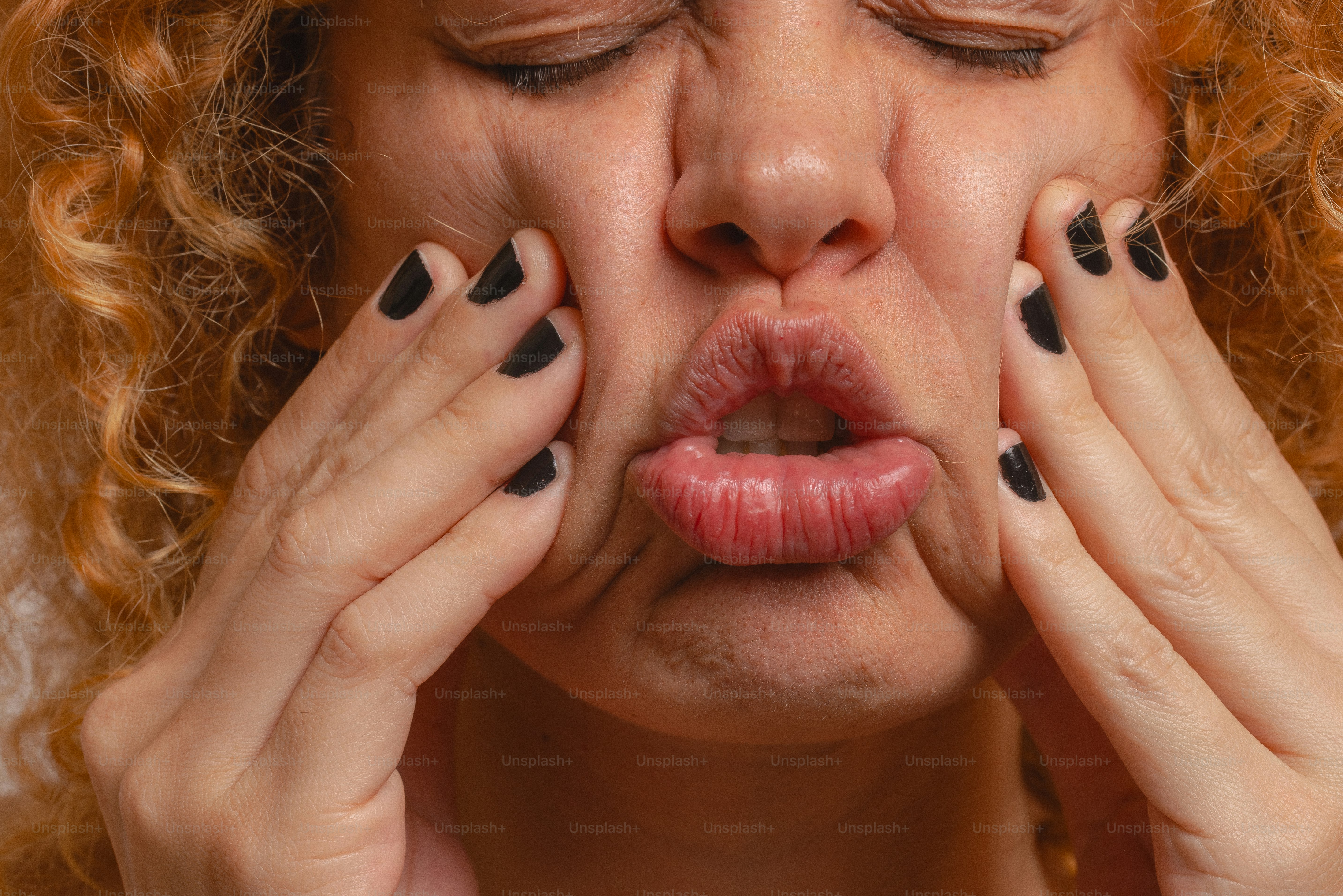 A woman squeezes her face, looking in discomfort.
